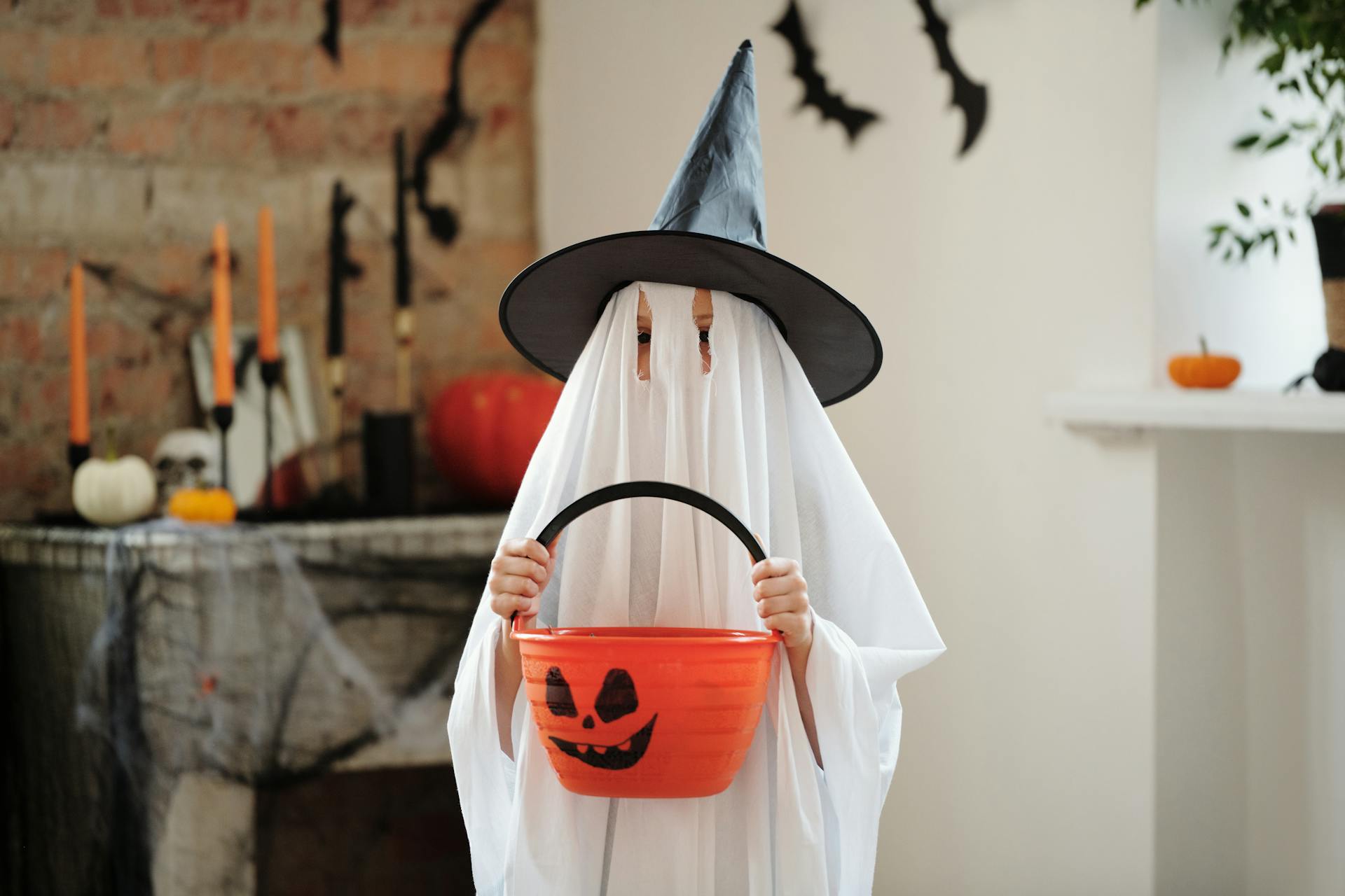 A child in a ghost costume holding a bucket | Source: Pexels