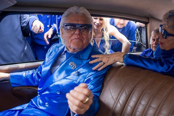 Michou, arrive à la flashMob de la Journée Michou à Paris, avec un code vestimentaire bleu. | Sources : Getty Images.