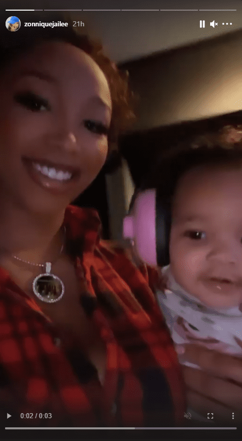 Zonnique Pullins smiles while holding her daughter, who has pink headphones on. | Photo: Instagram.com/zonniquejailee