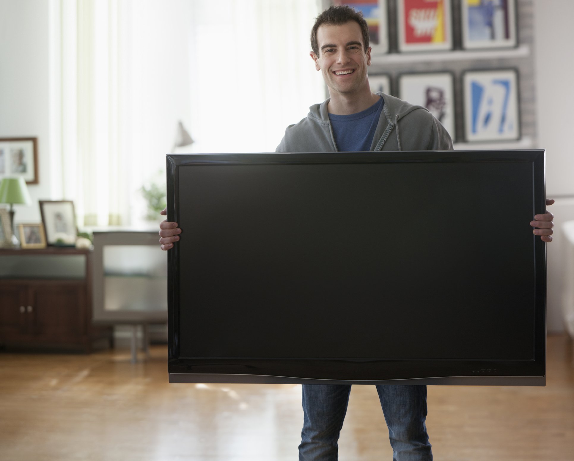 Photo of a young man carrying a TV | Photo: Getty Images