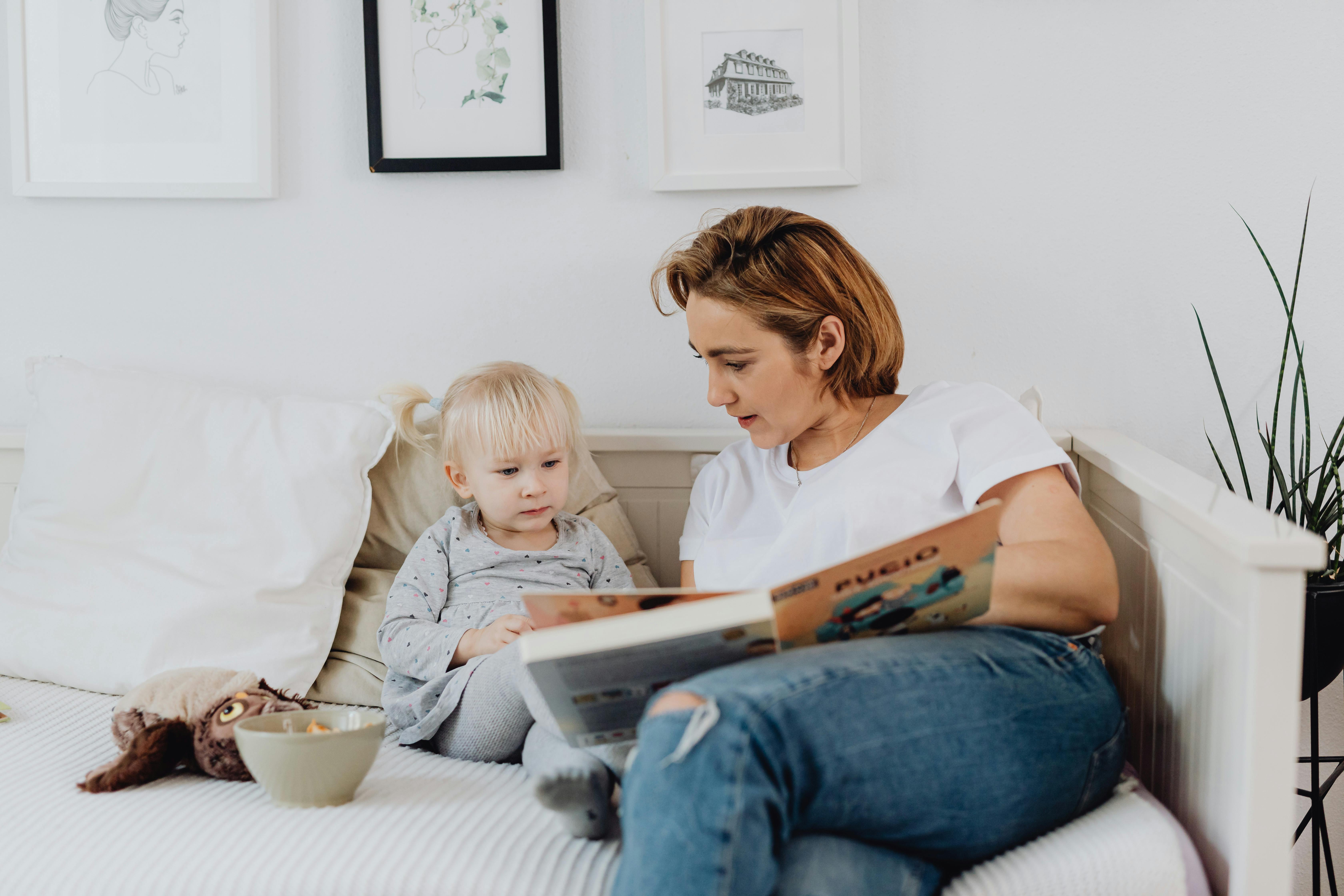 A woman reading a book to a child | Source: Pexels