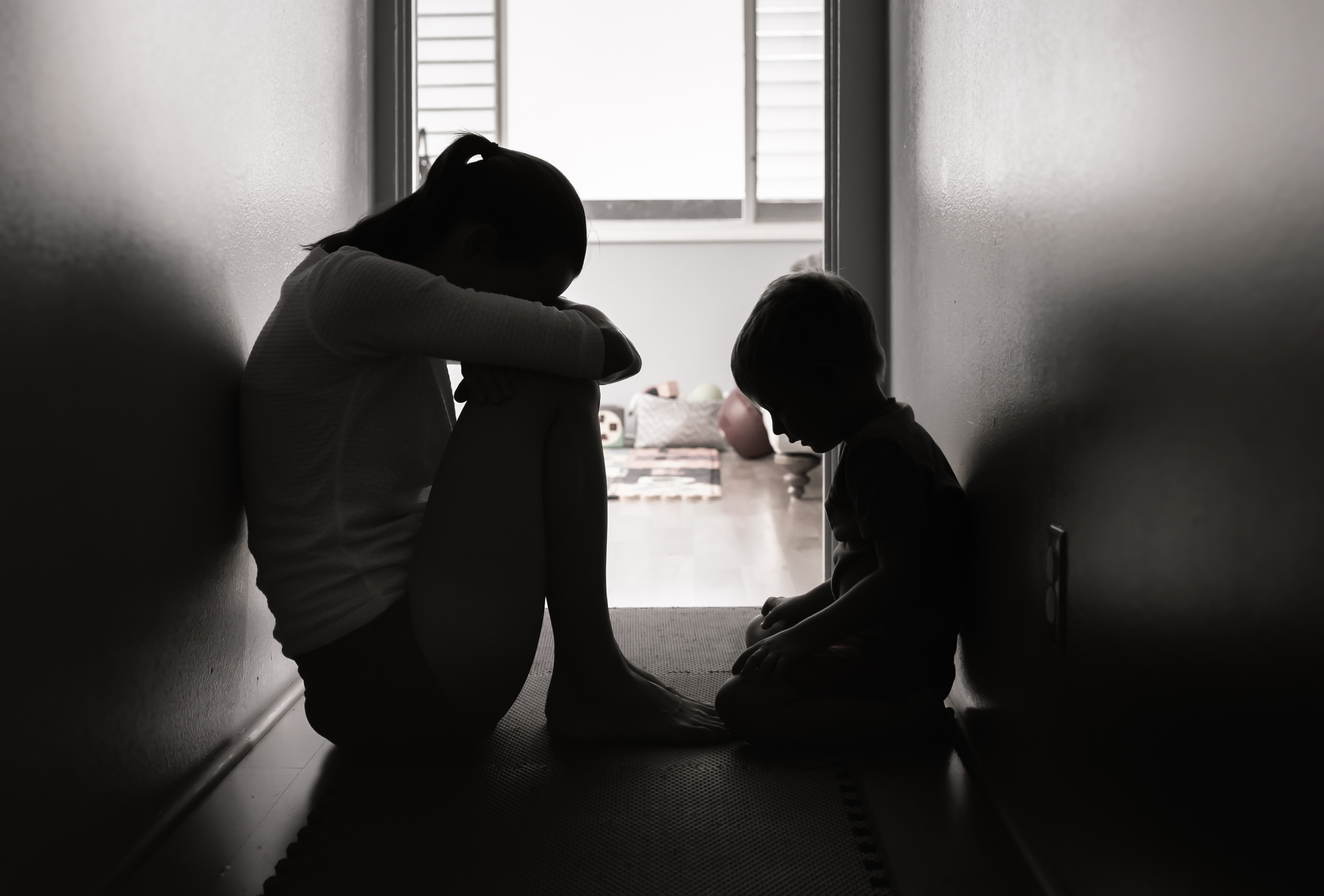 A woman and a boy sitting in a corridor with their heads bowed down | Source: Shutterstock