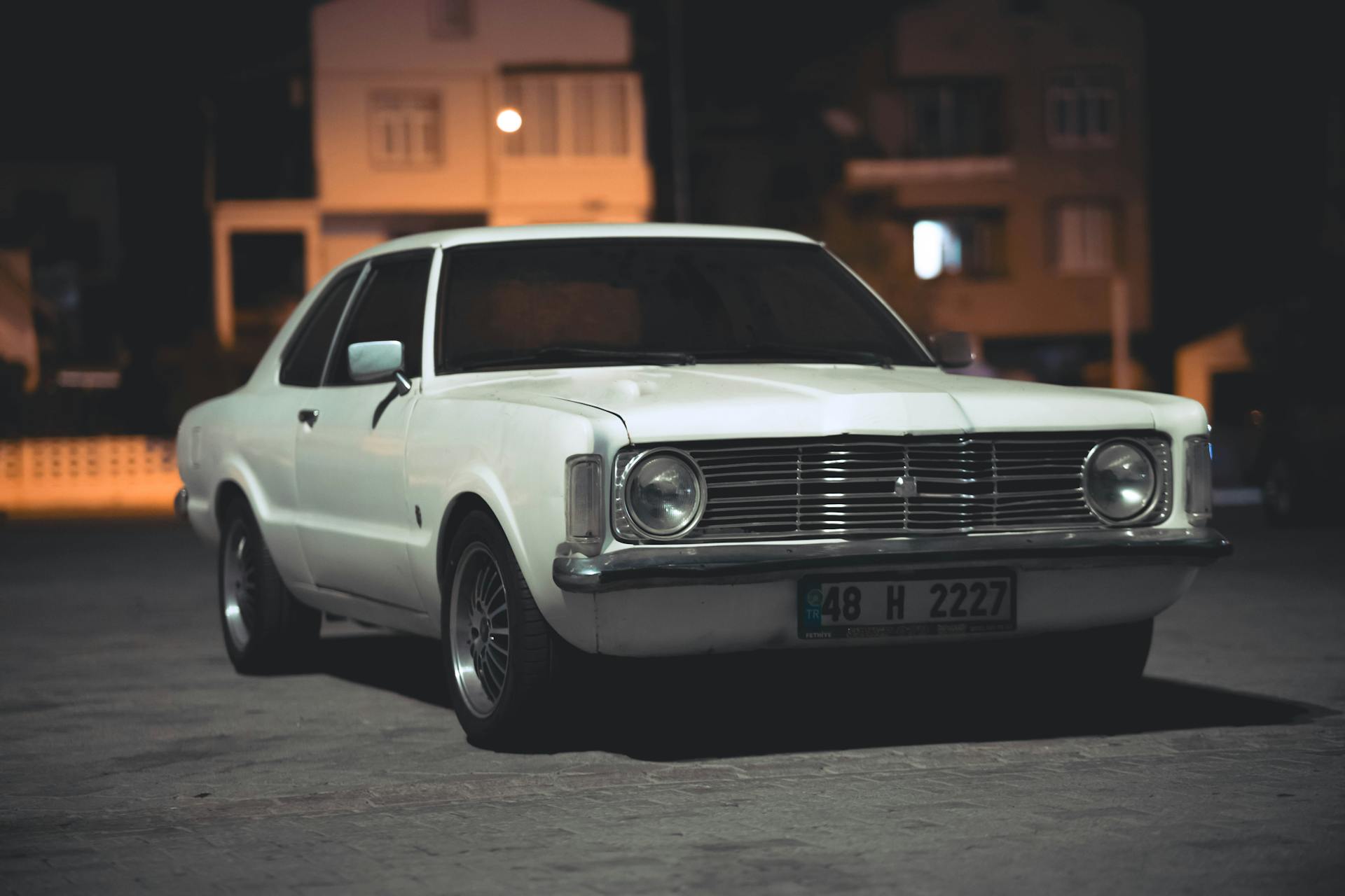 Un coche blanco clásico aparcado en una calle por la noche | Fuente: Pexels