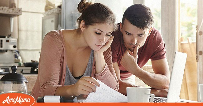 Woman in glasses and brunette man studying paper form bank while managing domestic budget together in kitchen interior | Photo: Shutterstock