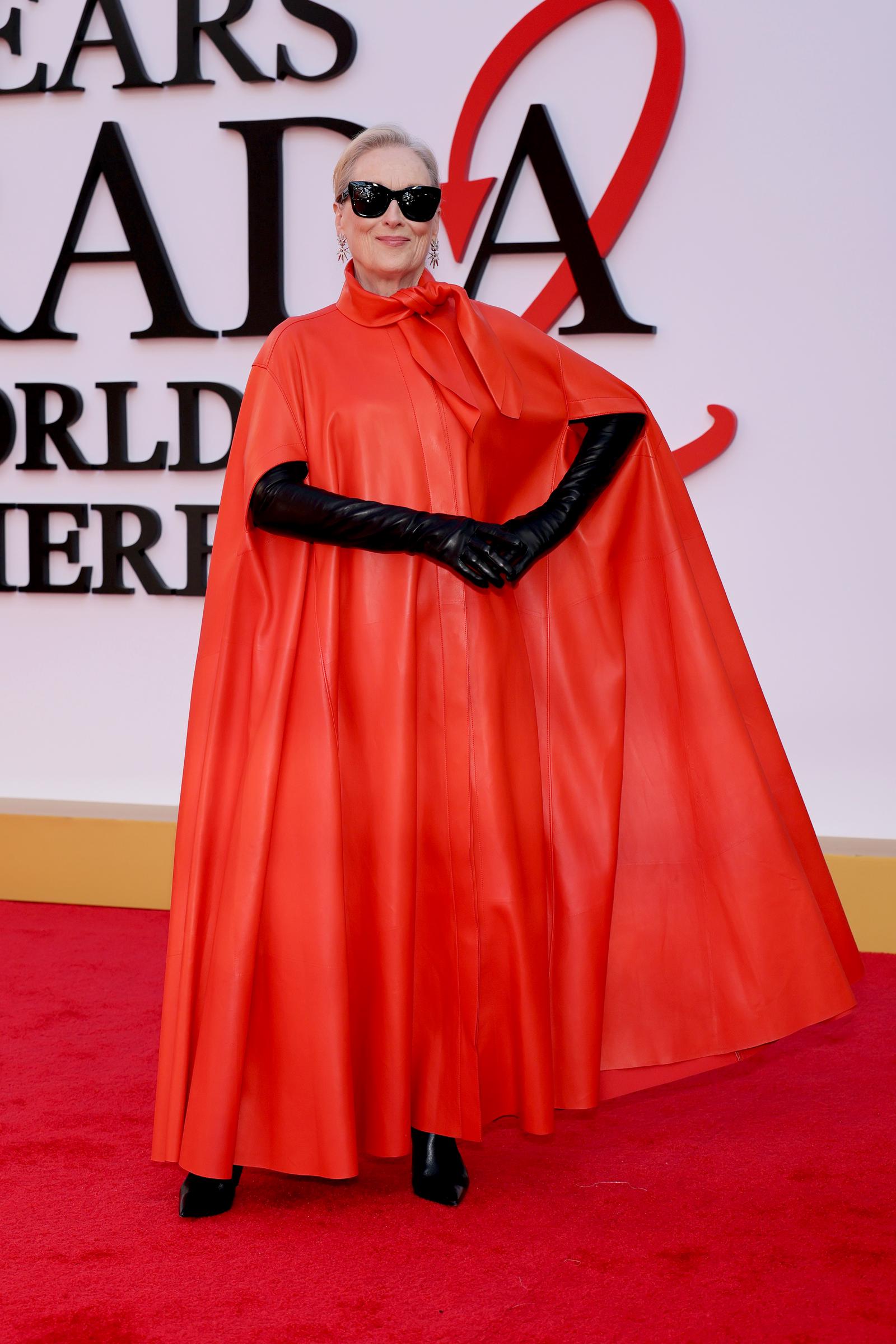 Meryl Streep pairs her striking red leather ensemble with elbow-length black leather gloves and pointed black ankle boots, accessorised with dangling crystal earrings.