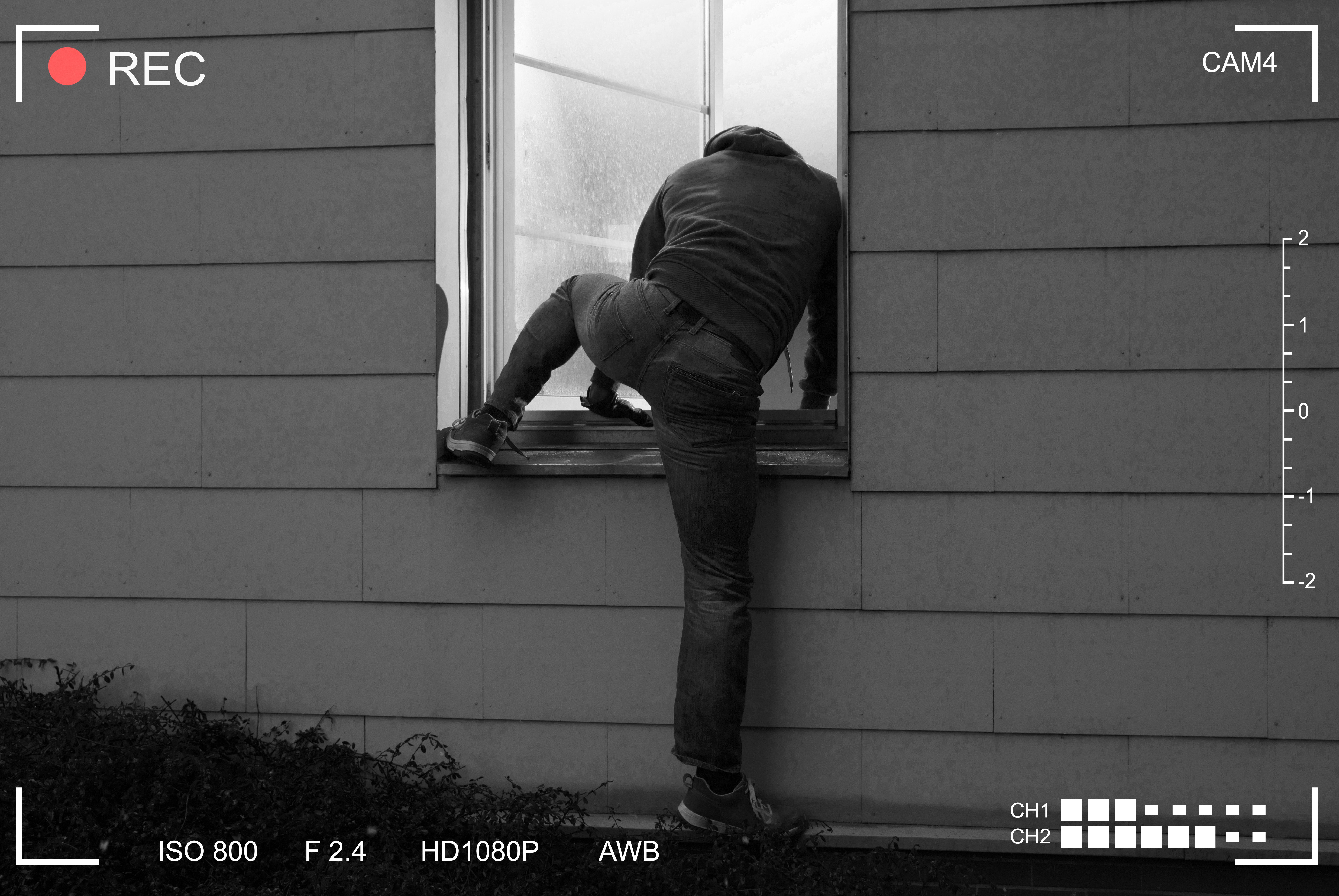 Thief is caught on camera as he attempts to break into a house via a window | Photo: Shutterstock/Andrey_Popov