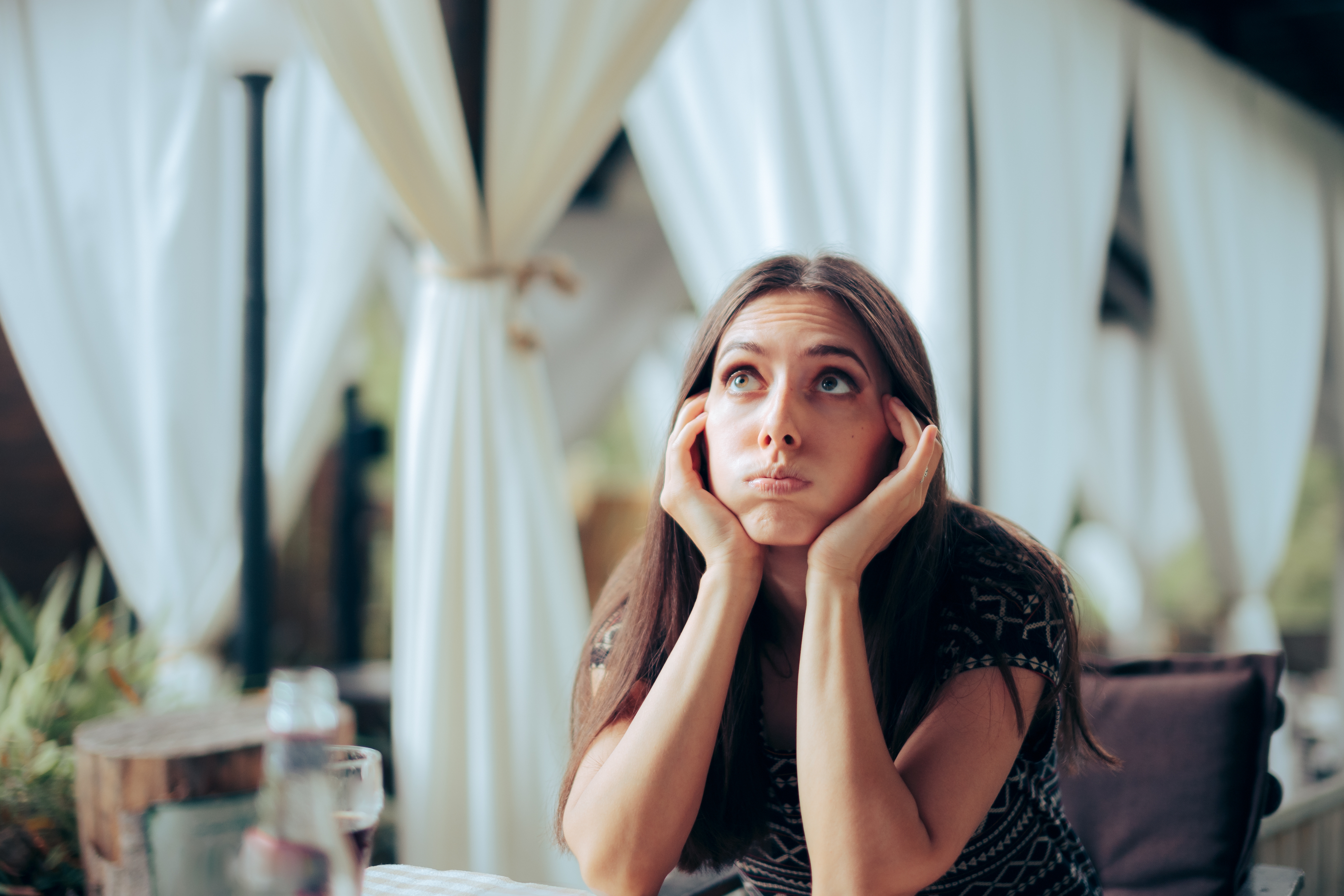 A woman sitting with her face resting on her palms | Source: Shutterstock