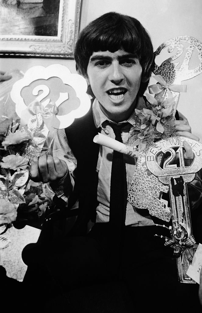 Beatles guitarist George Harrison posing with some of the gifts that fans sent him to celebrate his 21st birthday | Getty Images / Global Images Ukraine Beatles guitarist George Harrison posing with some of the gifts that fans sent him to celebrate his 21st birthday | Getty Images / Global Images Ukraine