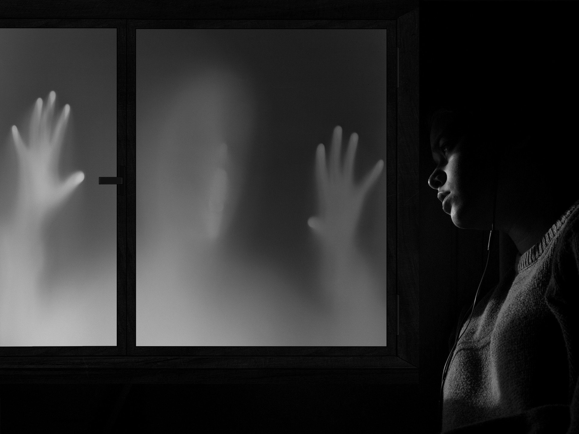 A boy looking at two hands and a face pressed up against a window | Photo: Pixabay