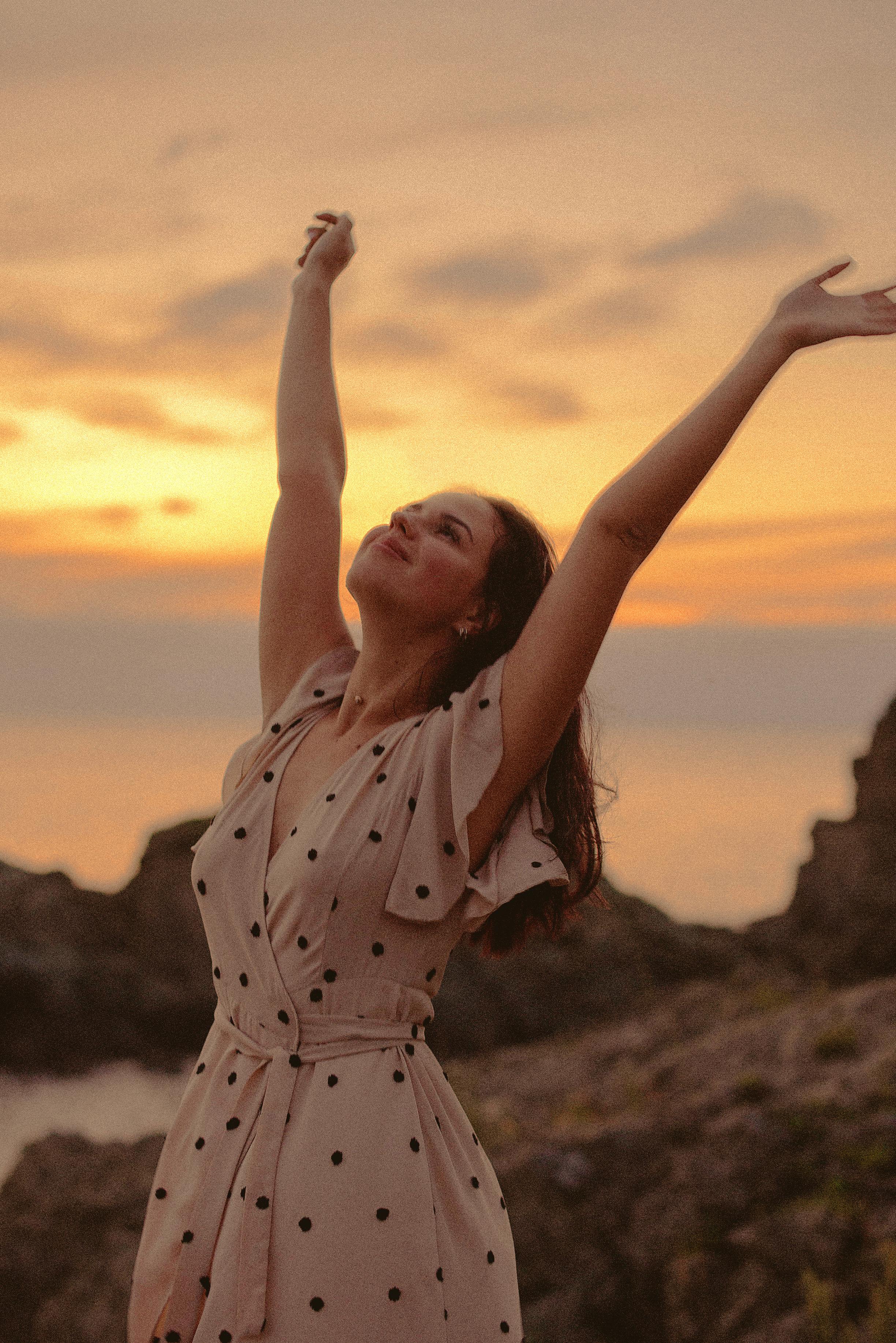 A happy and grateful woman looking up at the sky with outstretched arms | Source: Pexels