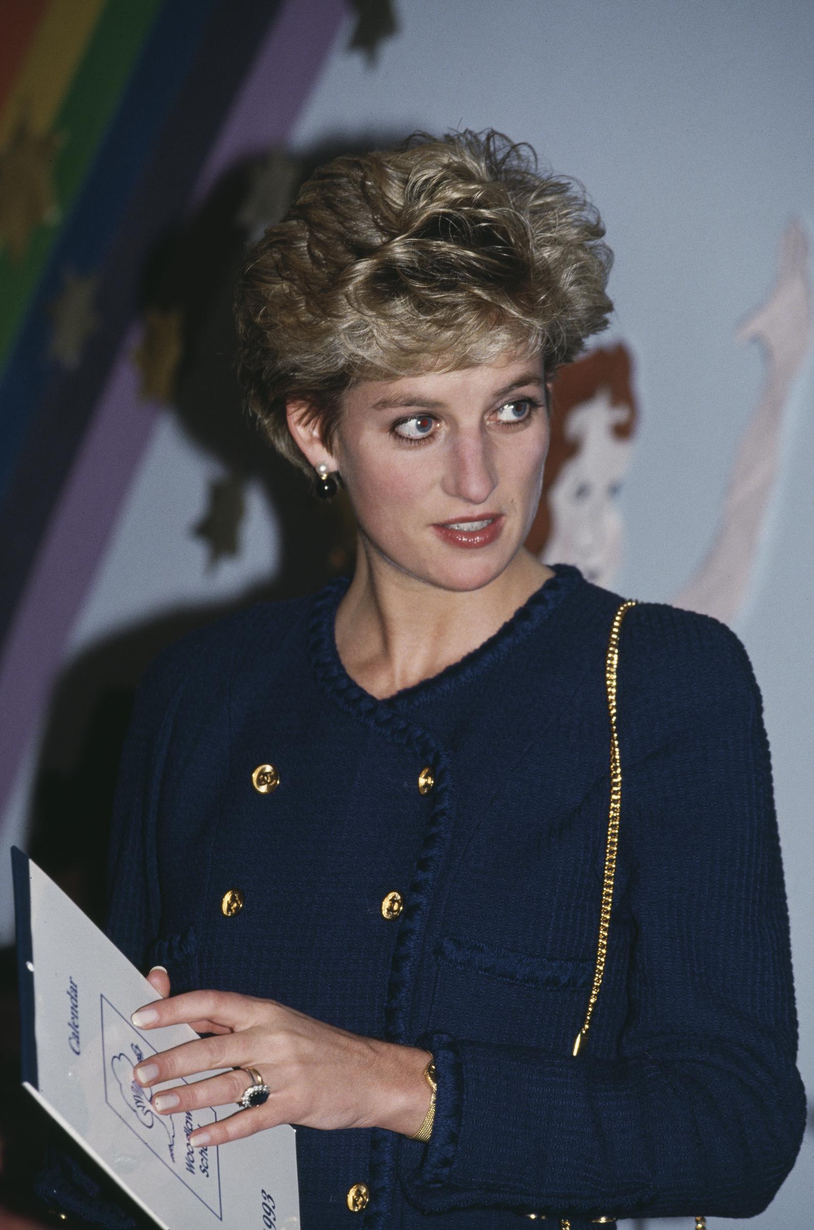 On December 9, 1992, the very day her separation from Prince Charles was publicly announced, Princess Diana carried on with royal duties at Woodlawn School for children with special needs in Tyne and Wear. Clutching the school’s 1993 calendar, she wore a composed expression and a navy suit accented with gold.