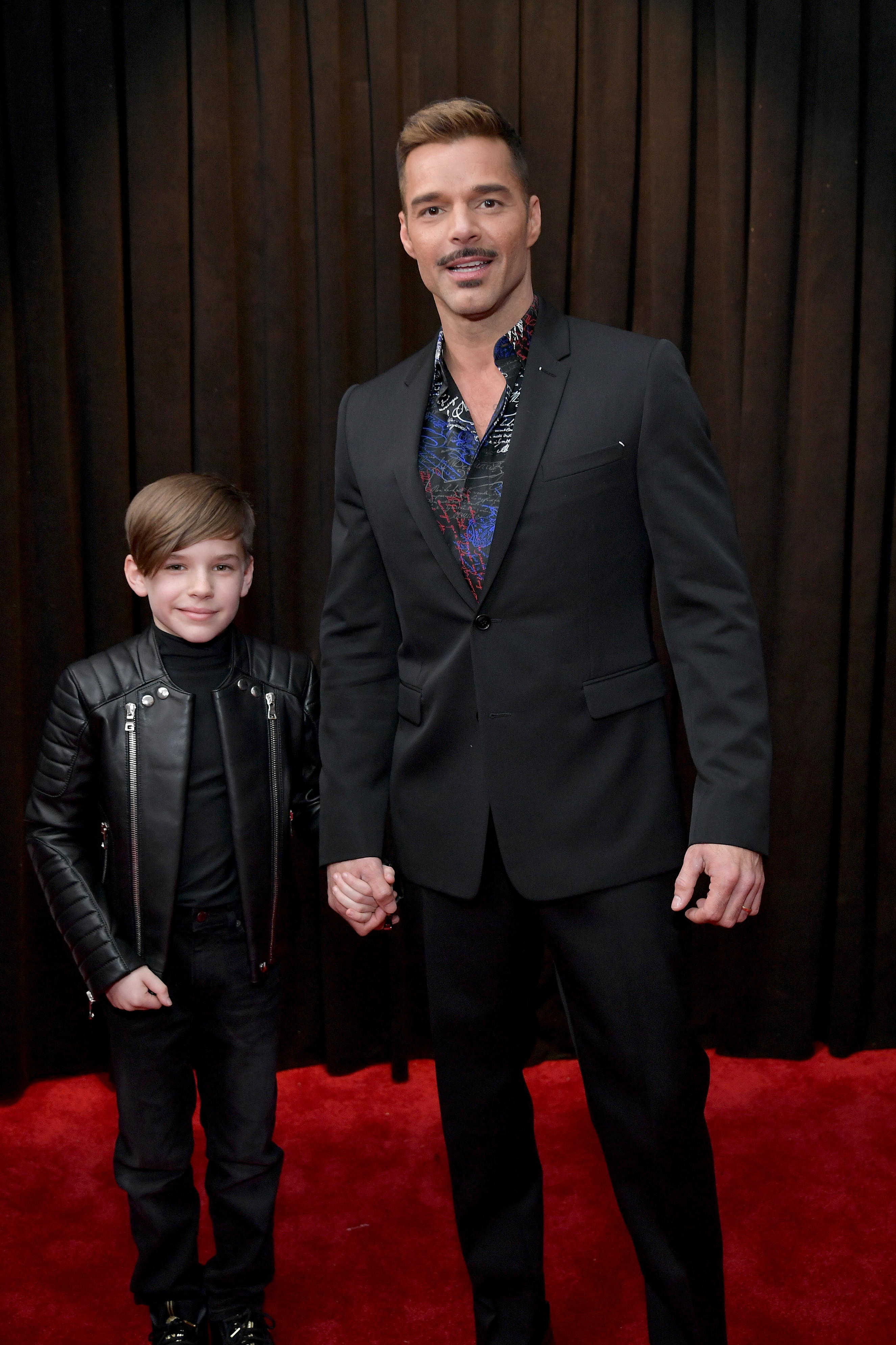 Ricky Martin holds one of his twin son's hand on the red carpet at the 61st Annual Grammy Awards, where both wear all-black looks.