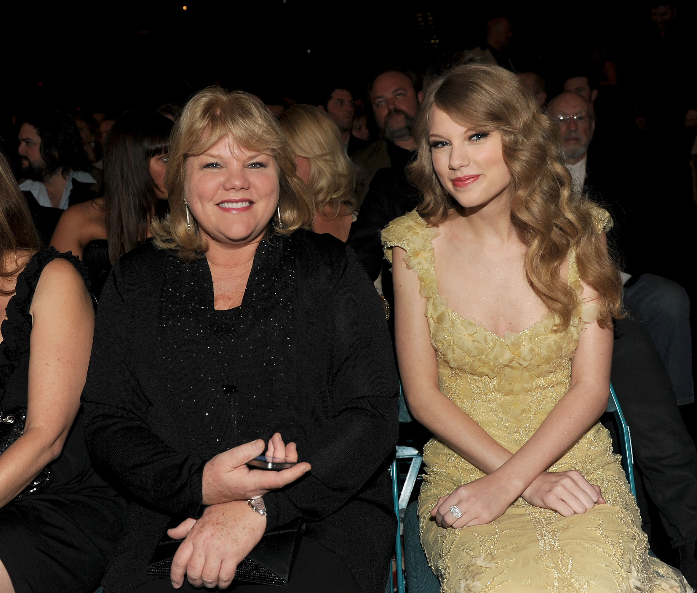 Taylor Swift and her mother, Andrea, sit together at the Academy of Country Music Awards in Las Vegas. Wearing a delicate yellow gown, Taylor shares a warm moment with her mother amid the night's country music celebrations.