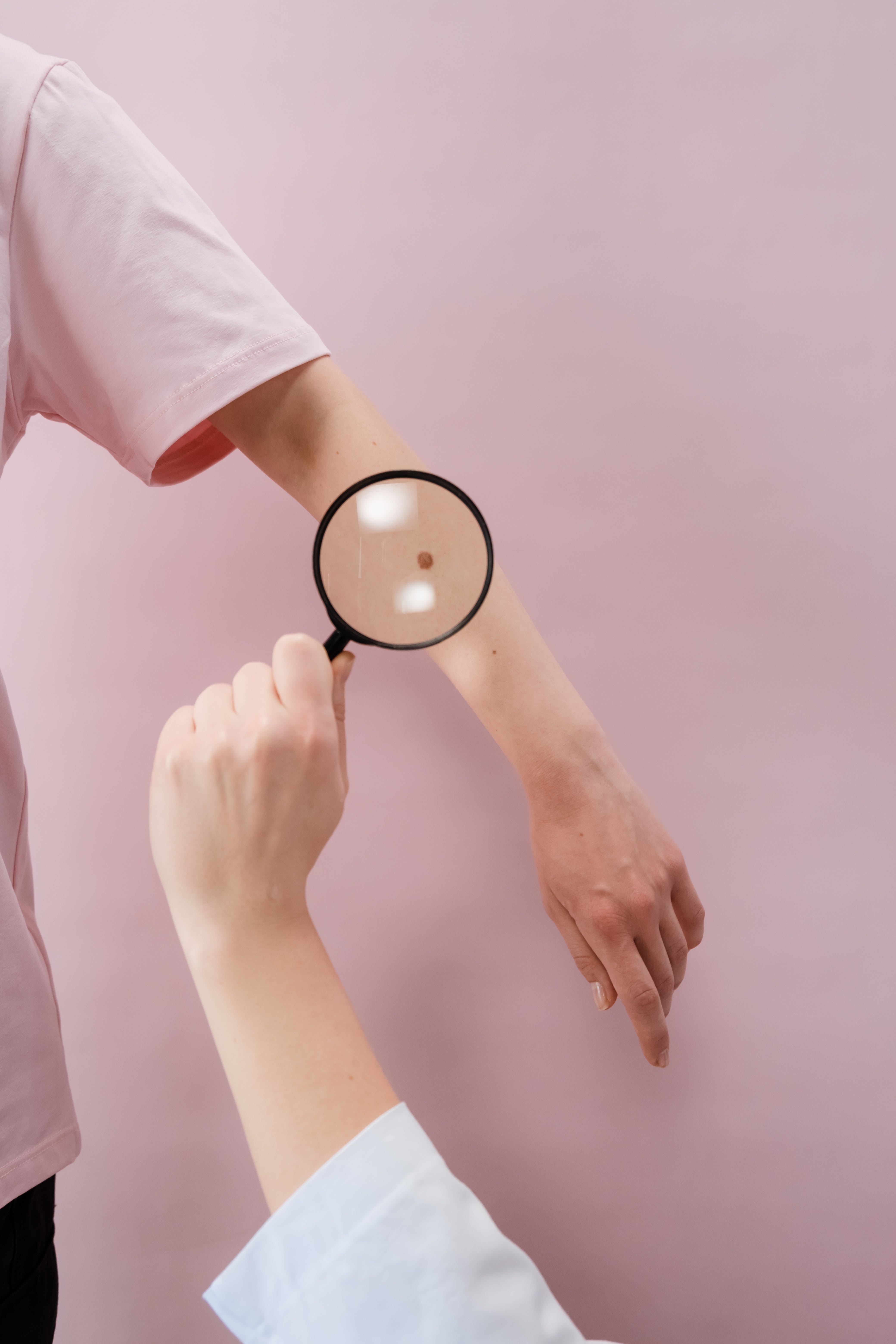 A doctor examining a patient's skin using a magnifying glass. | Source: Pexels