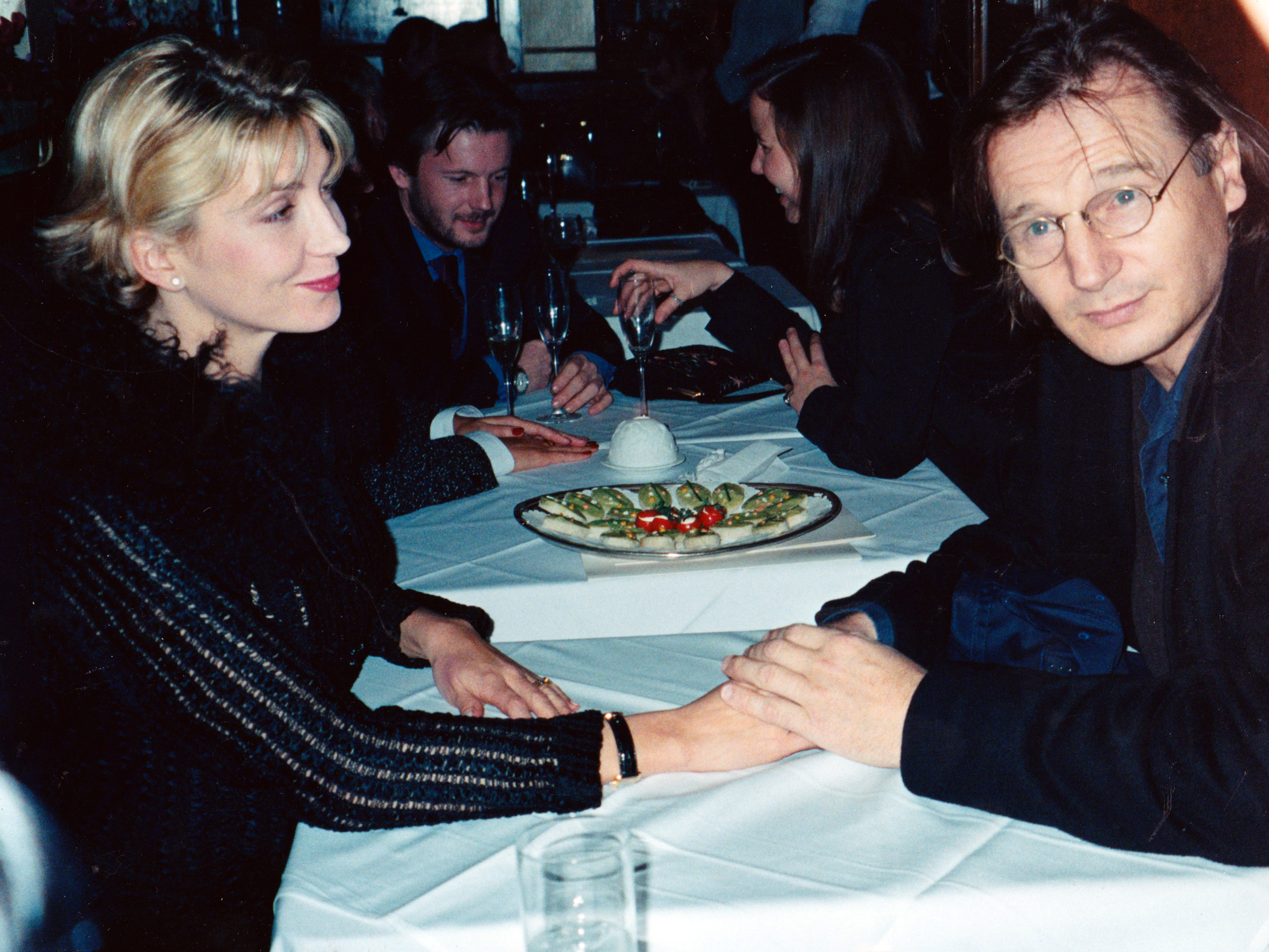 Liam Neeson holds Natasha Richardson’s hand during a dinner outing in New York City on January 1, 1997. Richardson gazes downward with a soft smile while Neeson looks toward the camera in the candid moment.