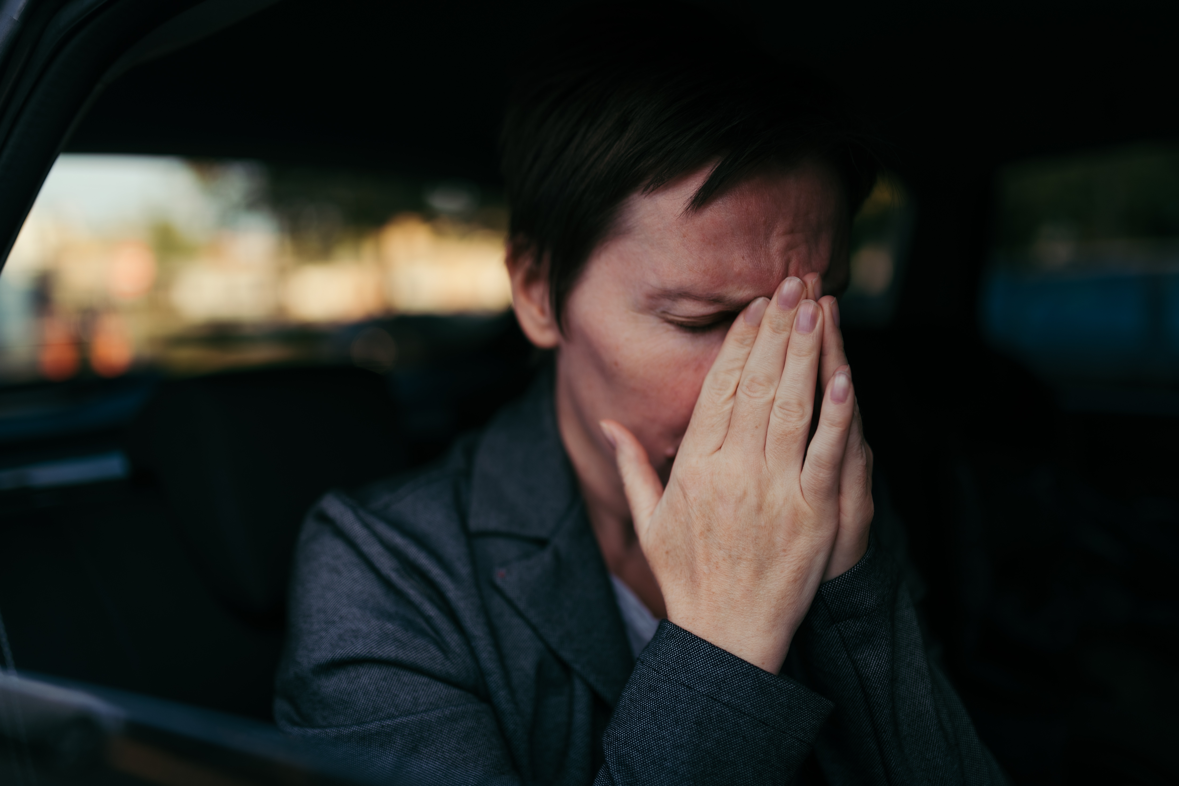 An anxious woman sitting in the back of a car | Source: Shutterstock