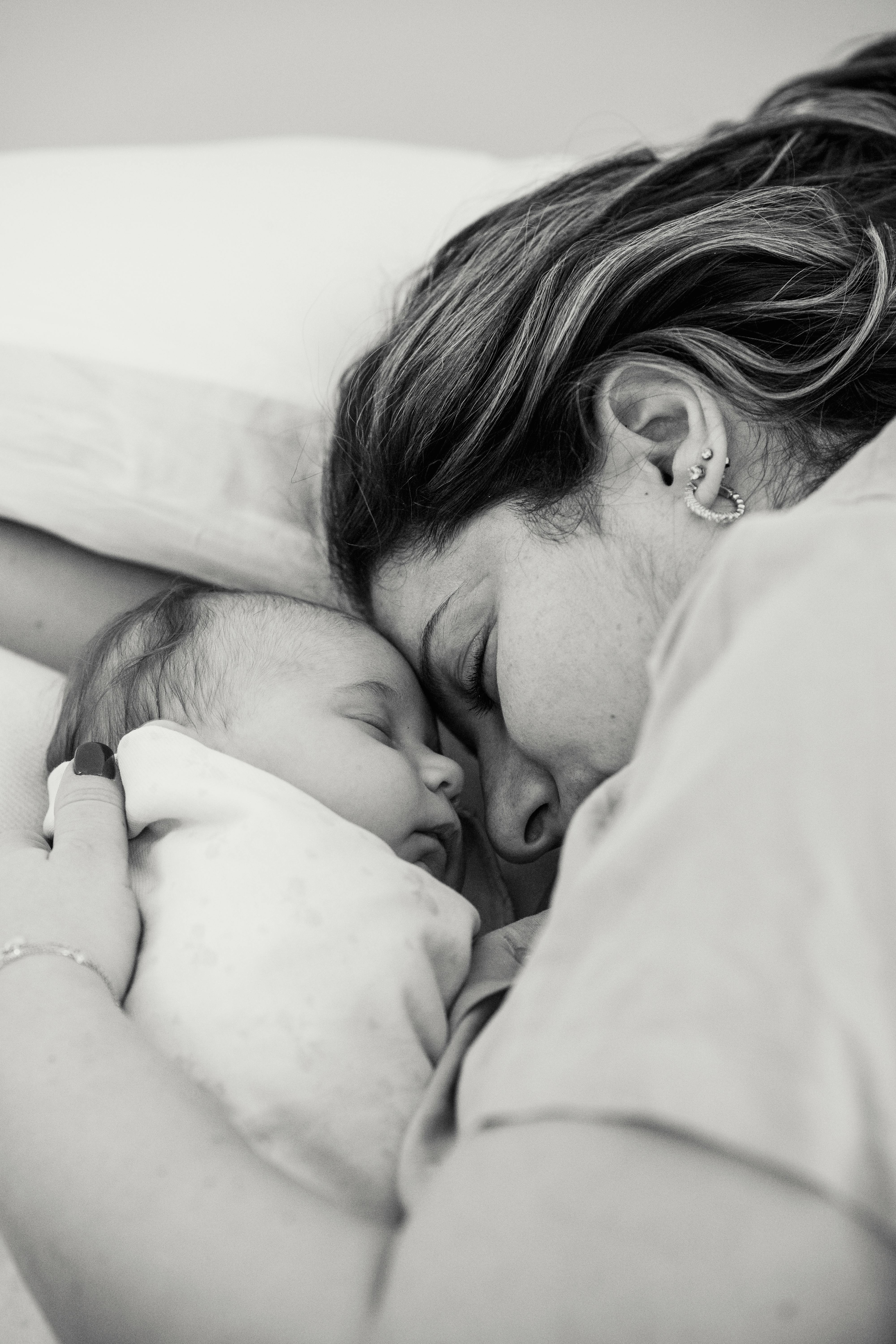 A mother sleeping on the bed while embracing her baby | Source: Pexels