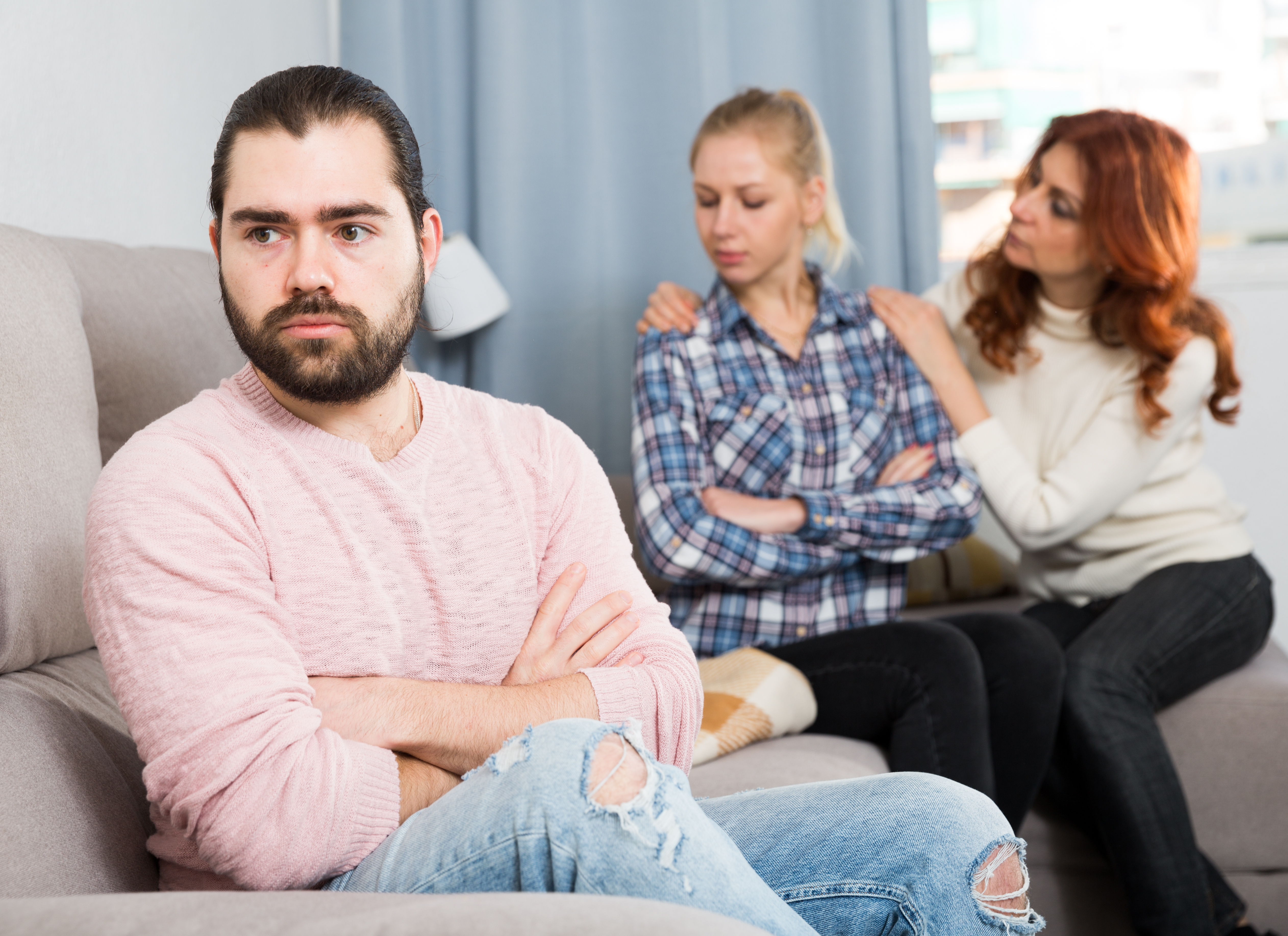 A middle-aged woman comforts a young girl while her son appears angry and displeased | Source: Shutterstock