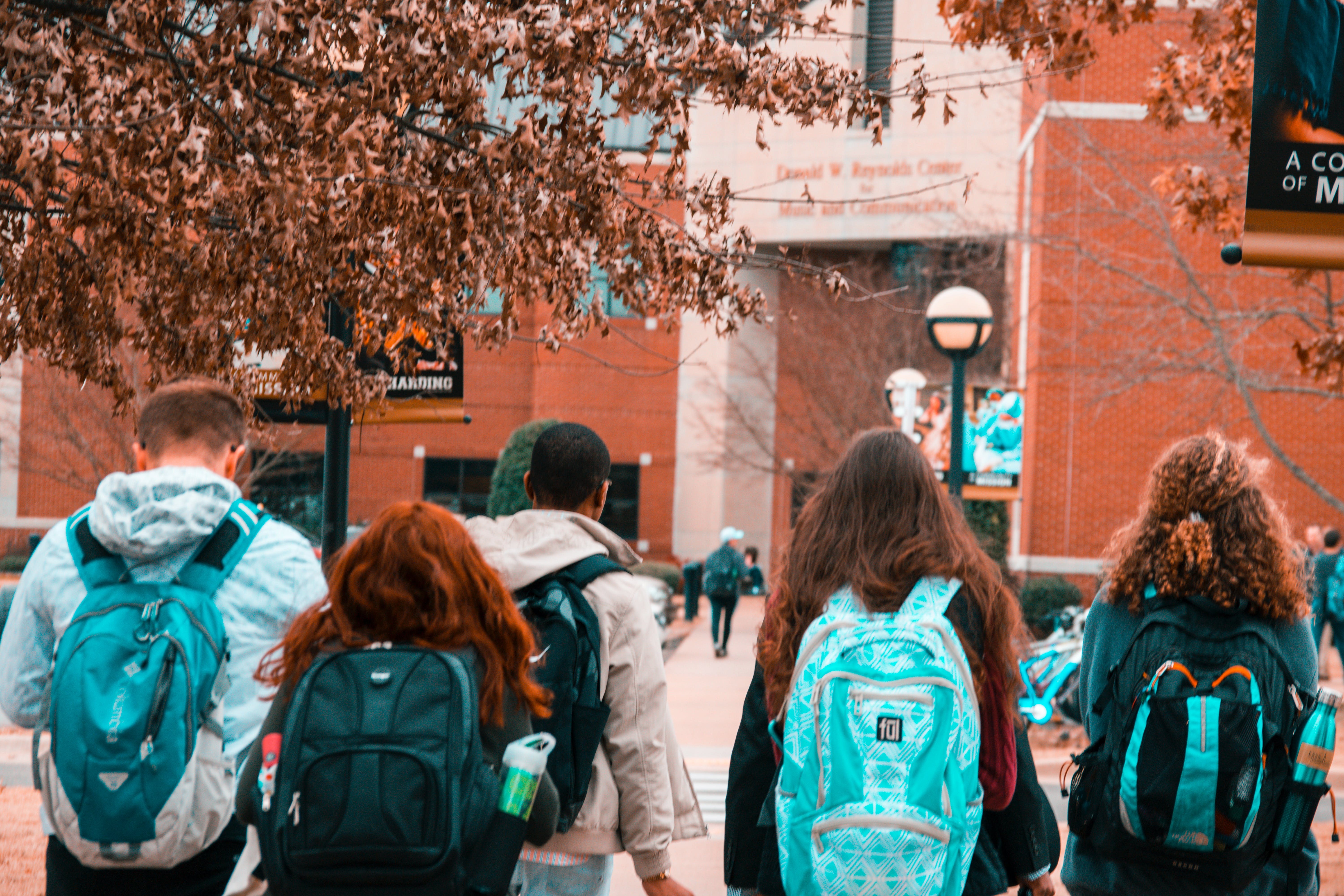 Students wearing backpacks while walking into a school | Source: Pexels