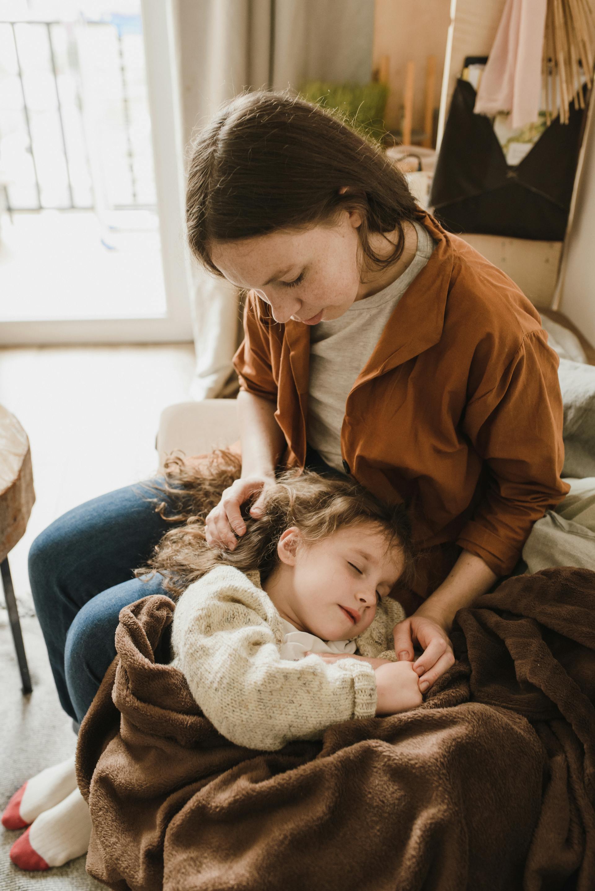 A little girl sleeping in her mother's lap | Source: Pexels