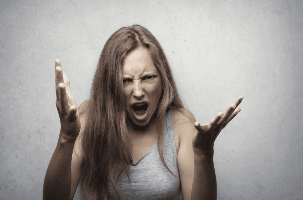 Eine wütende Frau in einer grauen Weste mit erhobenen Händen. | Quelle: Pexels