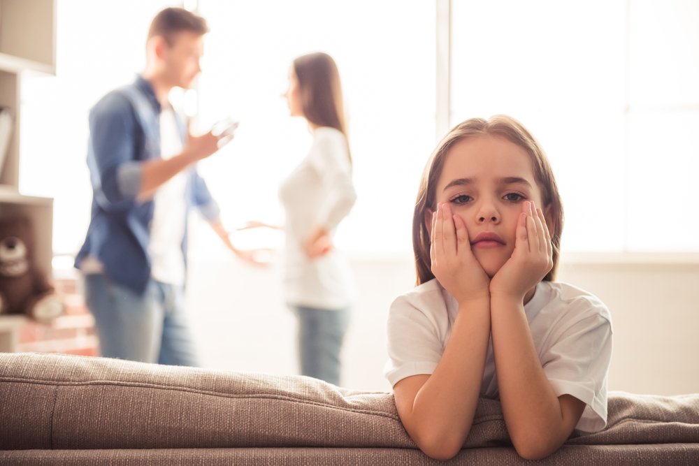 Sad little girl is looking while her parents are arguing in the background. | Photo: Getty Images