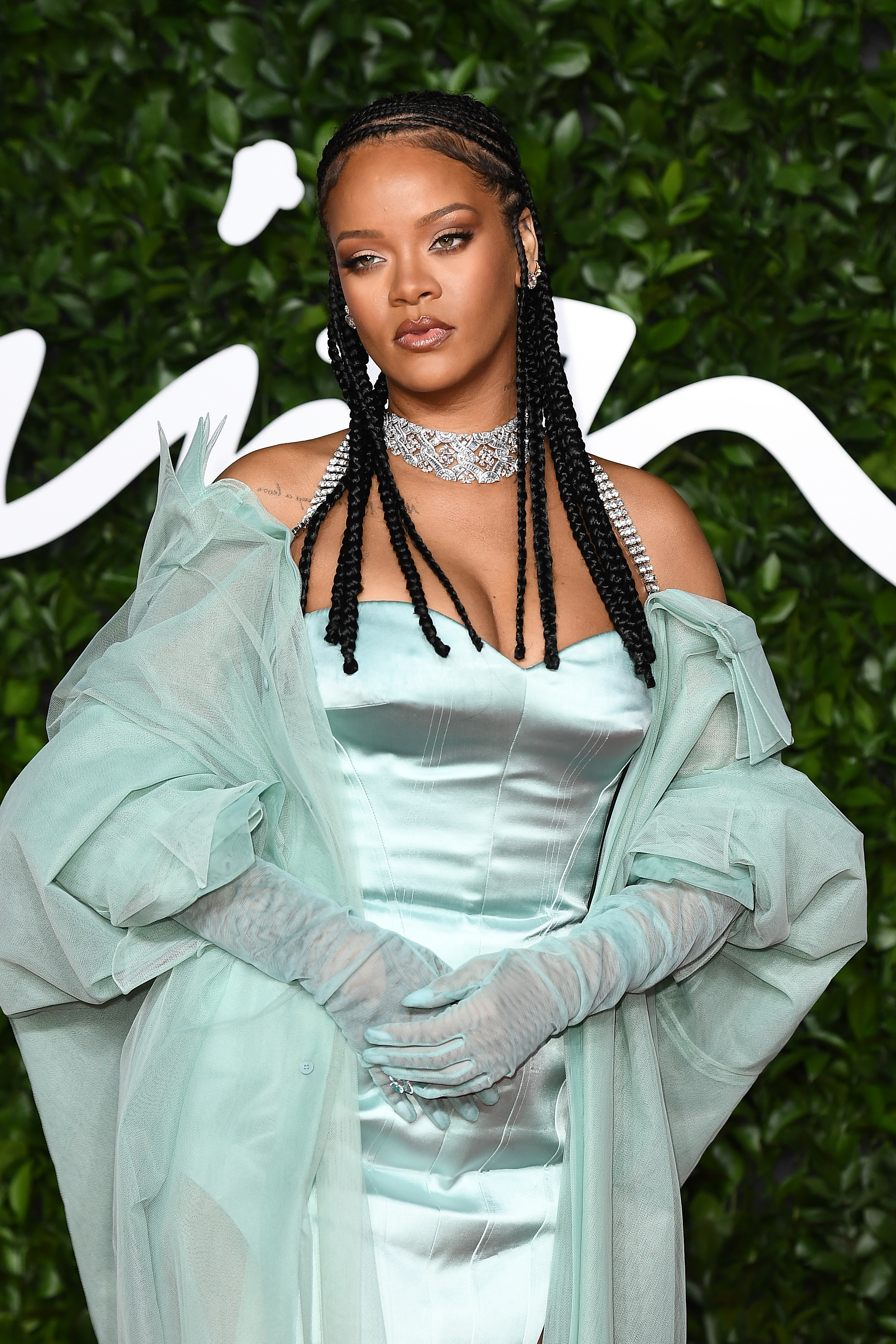 Rihanna arrives at the Royal Albert Hall in an icy blue gown that moves like liquid silk beneath airy tulle. Her long, sleek braids and a dazzling diamond choker frame a calm, commanding look, turning her Fashion Awards entrance into a moment of cinematic glamor.