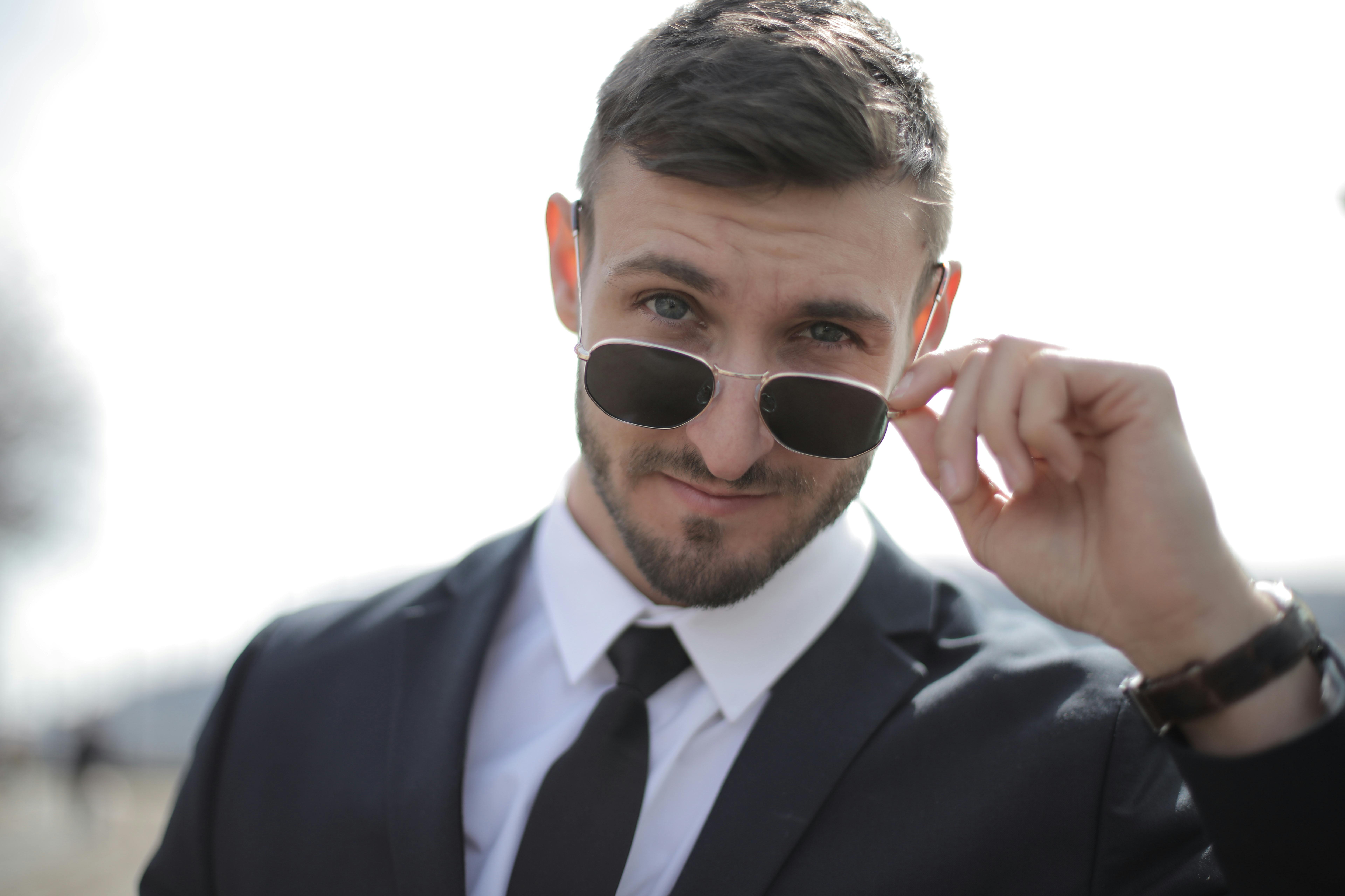 An arrogant man peeking over his glasses | Source: Pexels