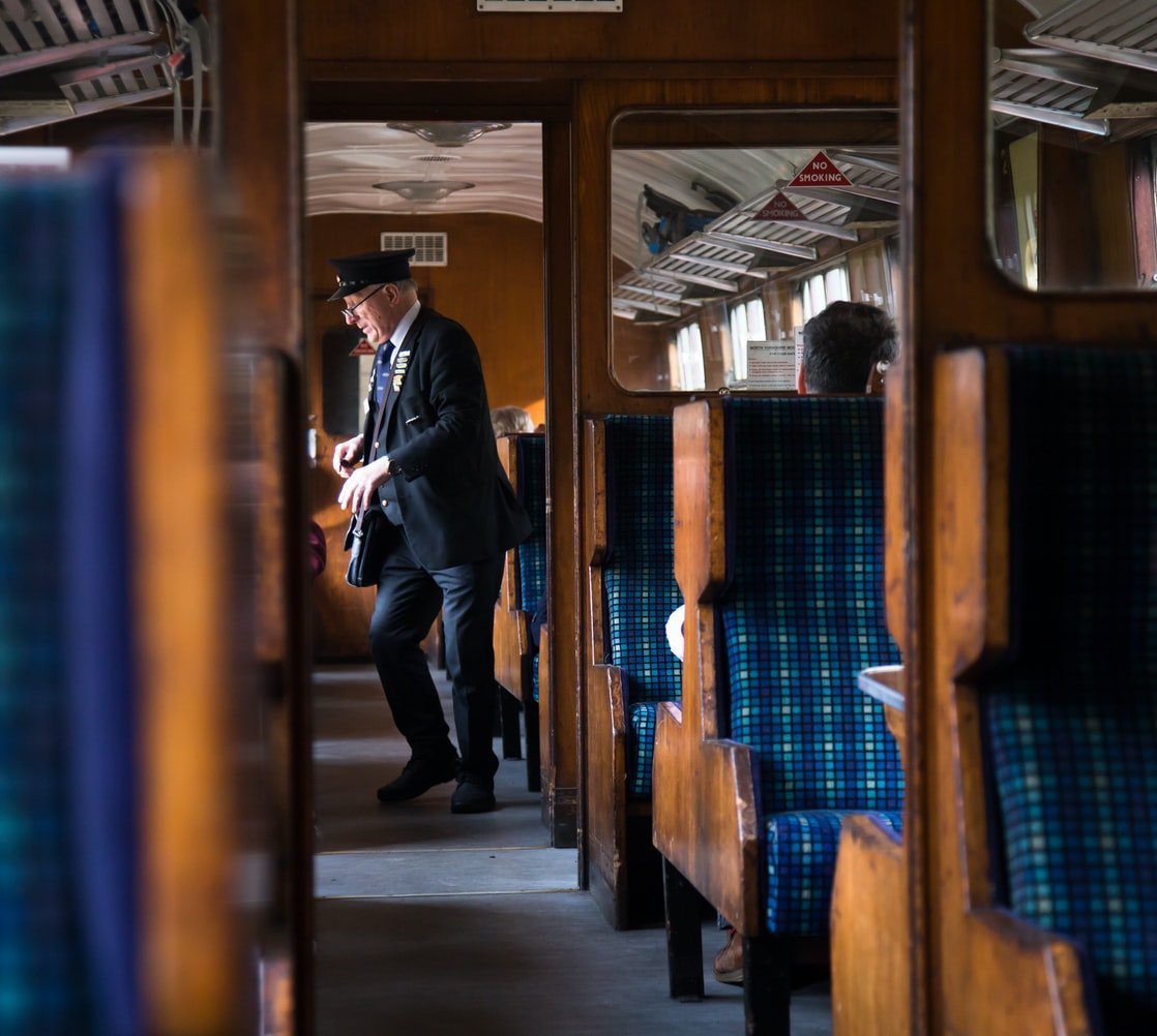 The train conductor is checking people’s tickets. | Photo: Unsplash/Johnny Rothwell