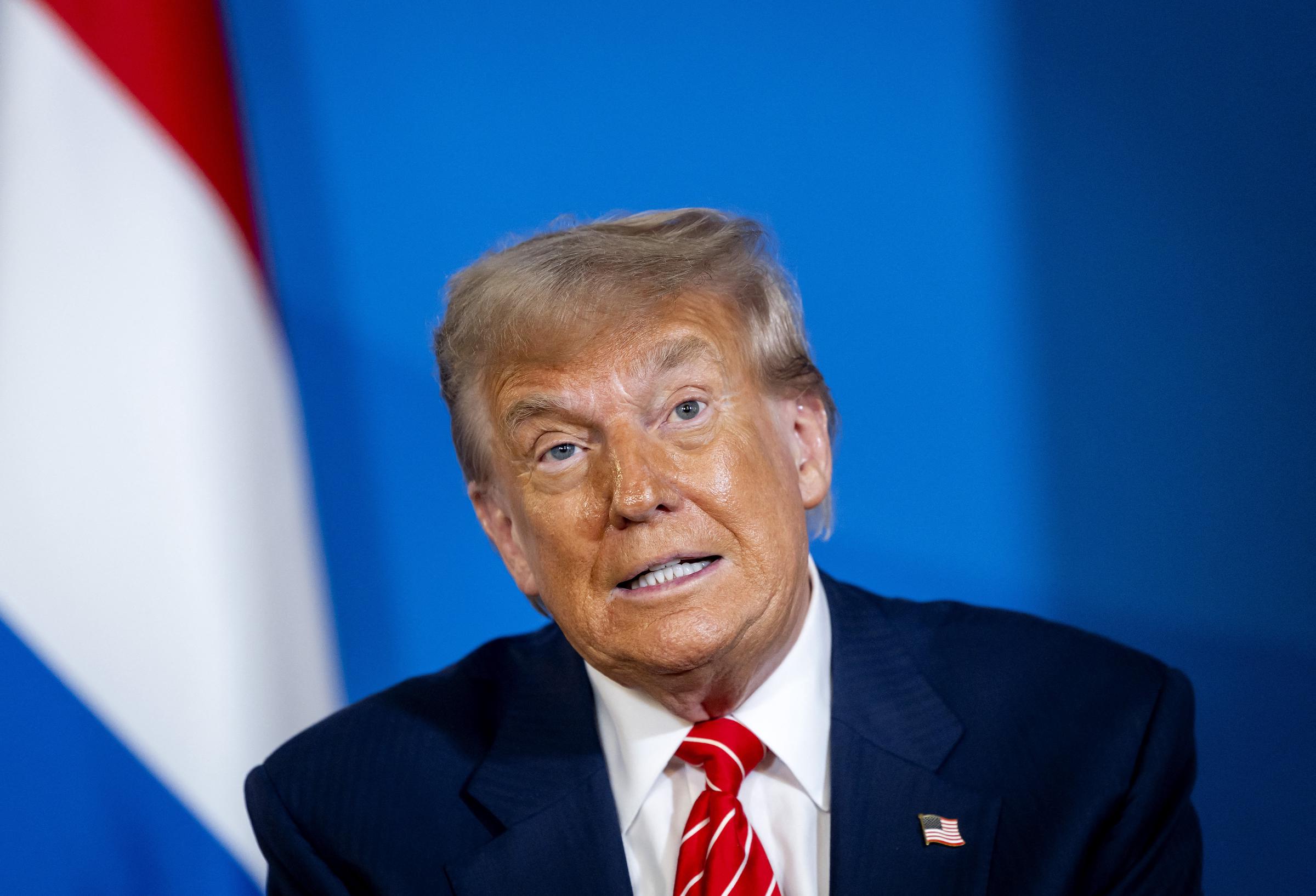 Trump gestures during his meeting with Schoof on the sidelines of the summit, the camera zooming in on his face. His expression remains controlled, his emotions carefully concealed as he speaks.