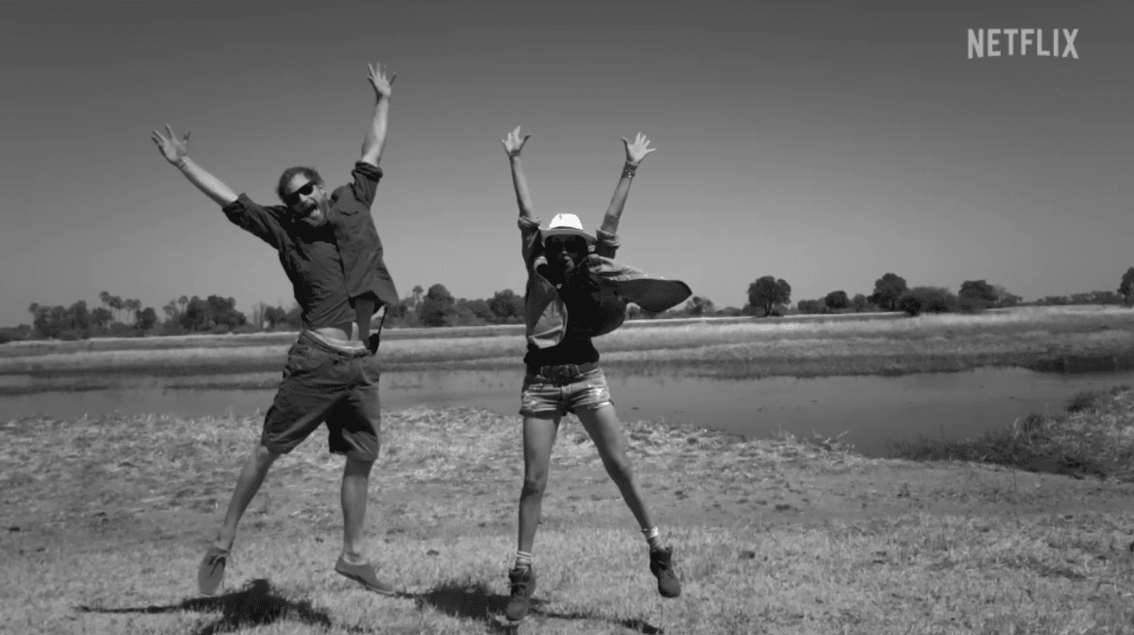 Harry and Meghan appear happy as they jump in the air in front of a lake, smiling | Source: youtube.com/netflix