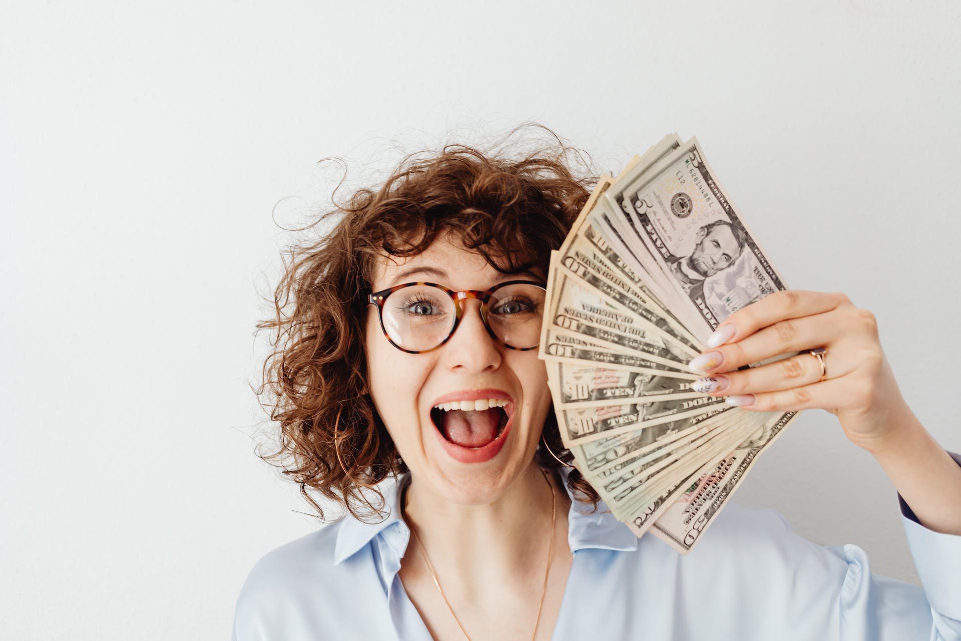 A happy woman holding dollar bills | Source: Pexels