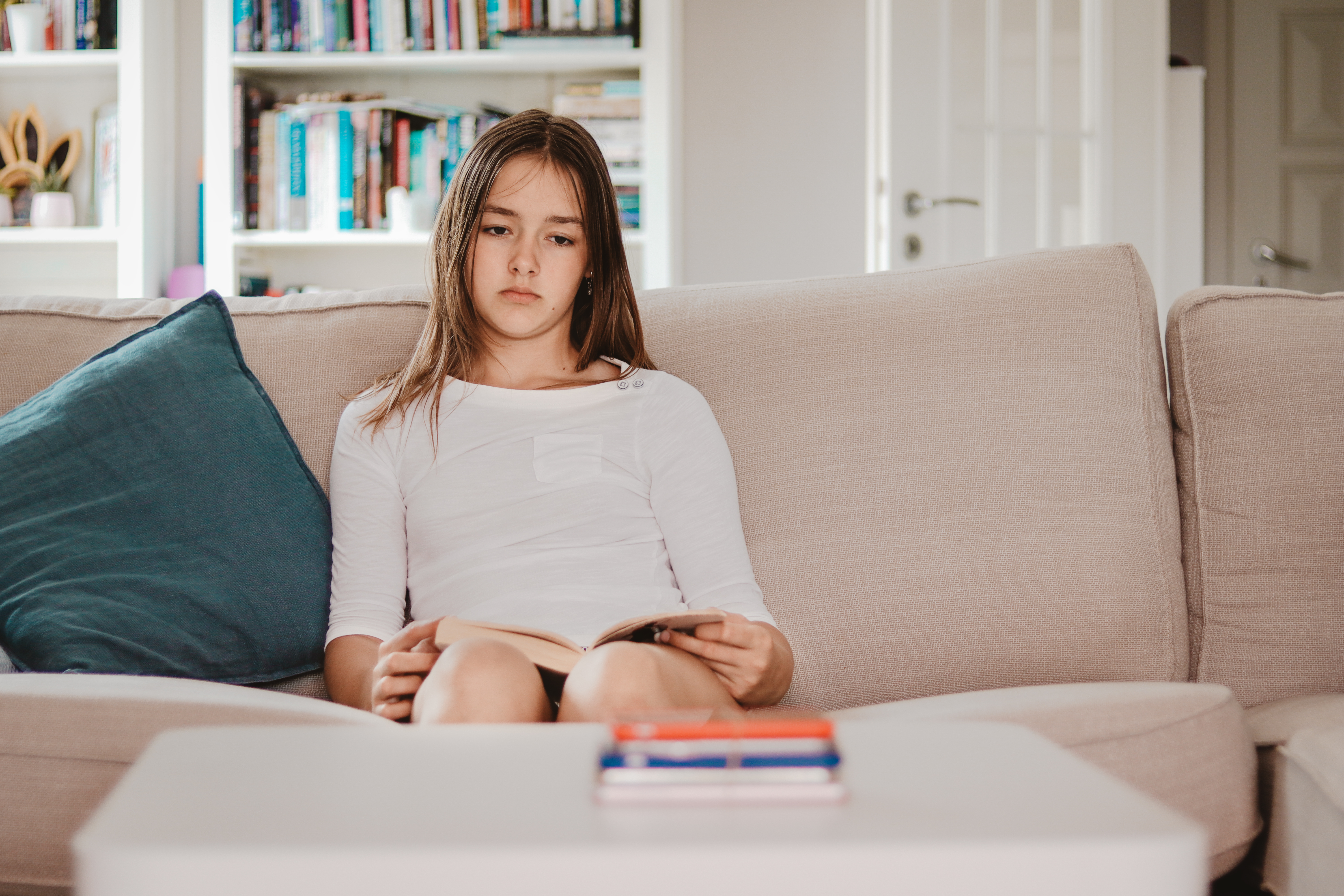 A young girl sitting on a couch looking sad | Source: Shutterstock