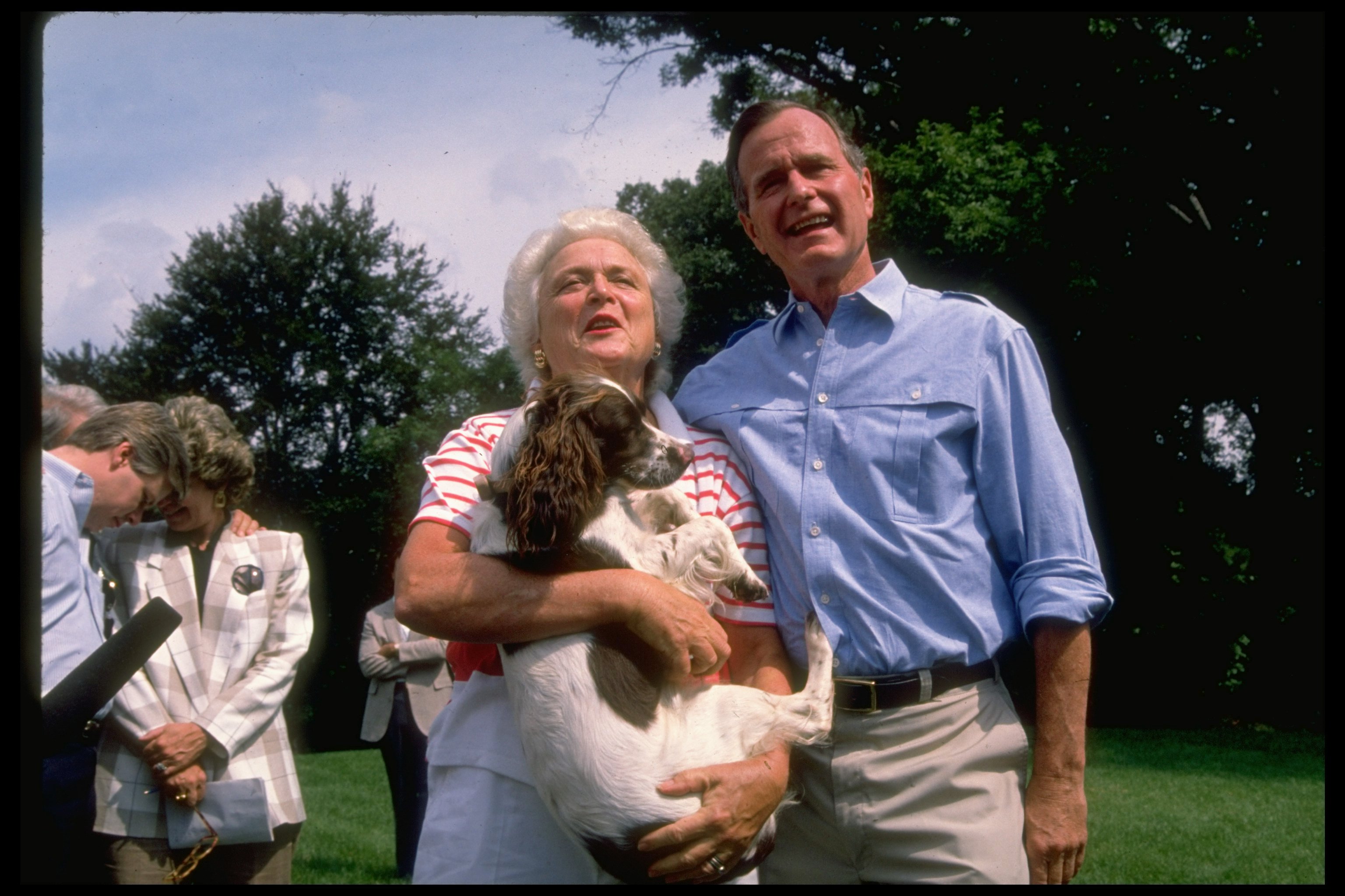 George & Barbara Bush speaking to reporters on lawn of their home at Naval Observatory, she holding family dog Millie. | Source: Getty Images