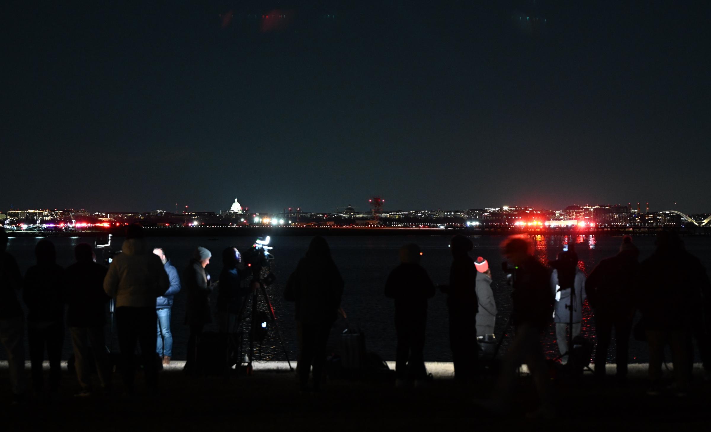 Press members work near the crash area after the plane collided in midair with the military helicopter and crashed into the Potomac River. | Source: Getty Images