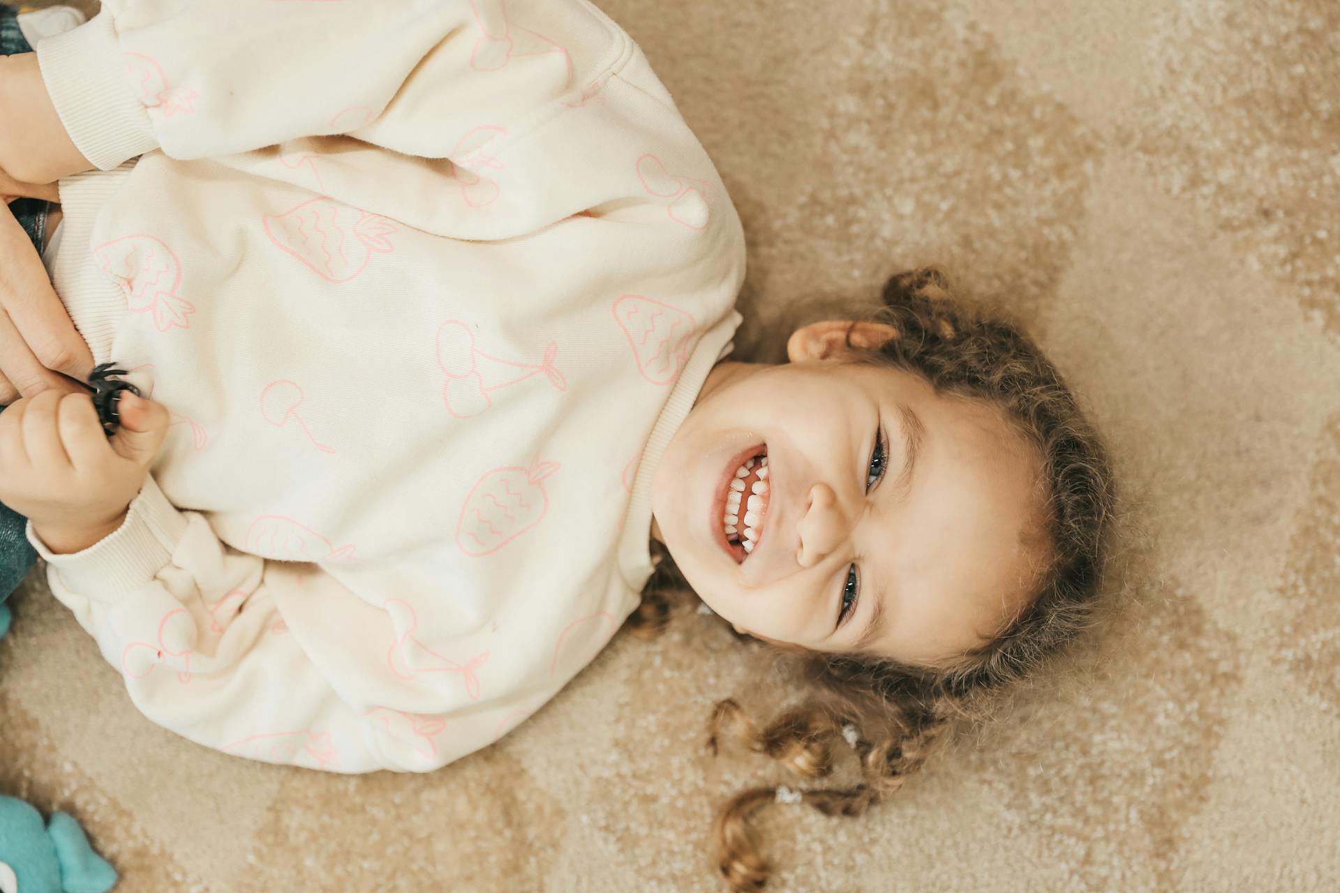 A smiling child lying on the floor | Source: Pexels