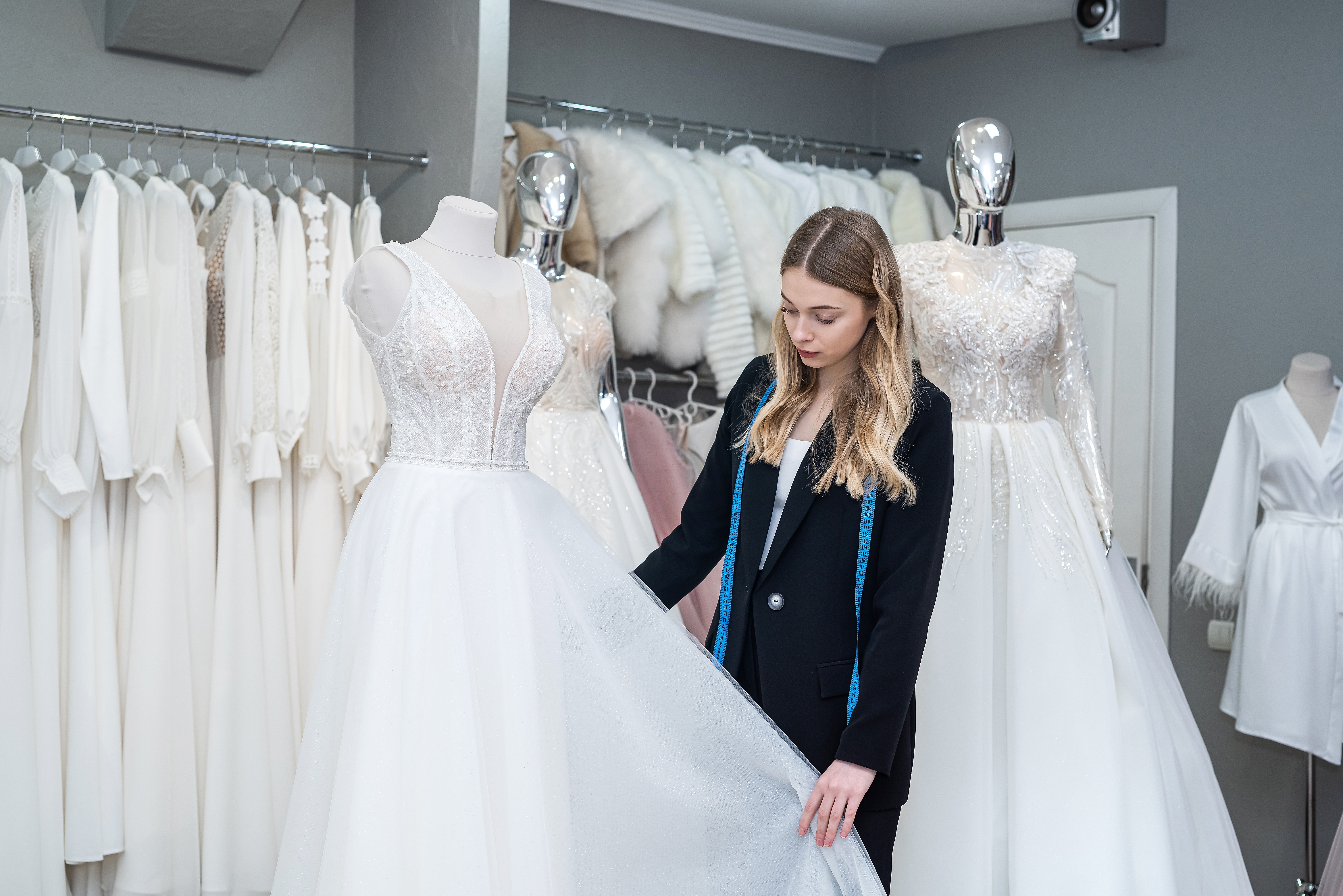 A designer taking measurements of a wedding dress | Source: Shutterstock