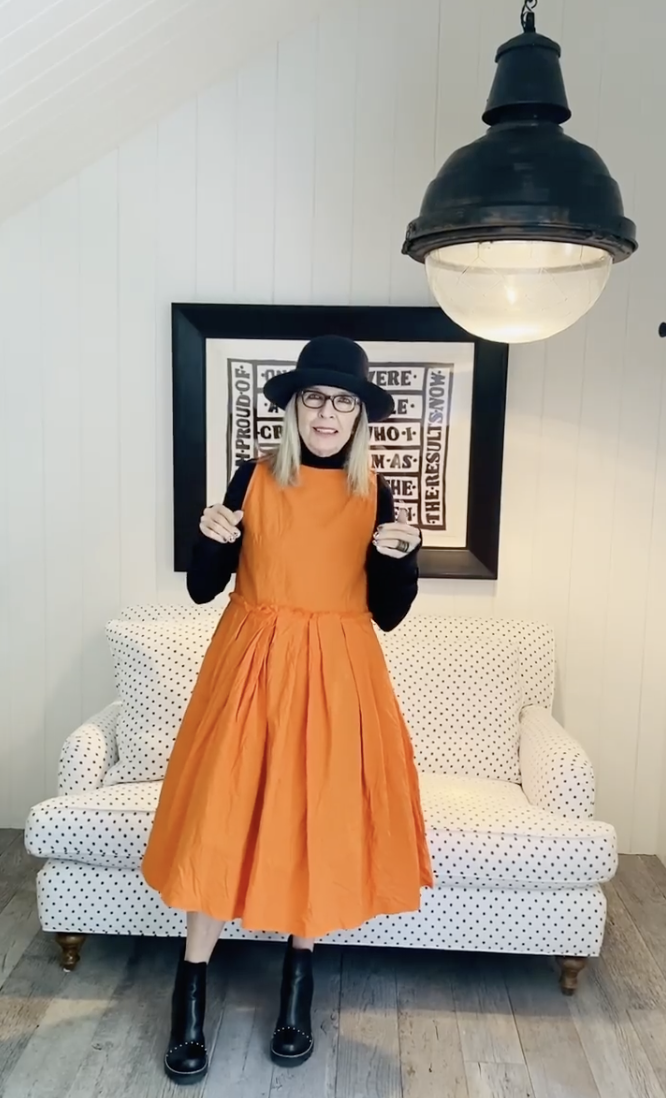 Diane Keaton pictured in an orange dress standing beside a polka-dot settee inside her Sullivan Canyon home, dated July 17, 2020 | Source: Instagram/diane_keaton