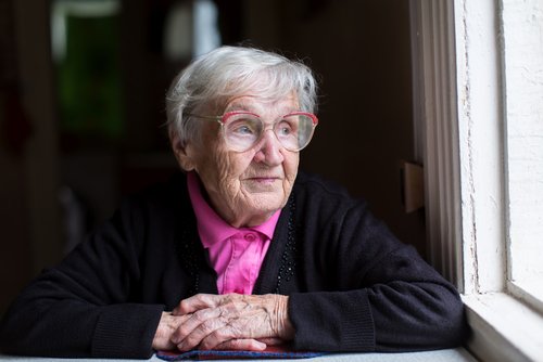 Anciana mirando a través de una ventana. | Foto: Shutterstock