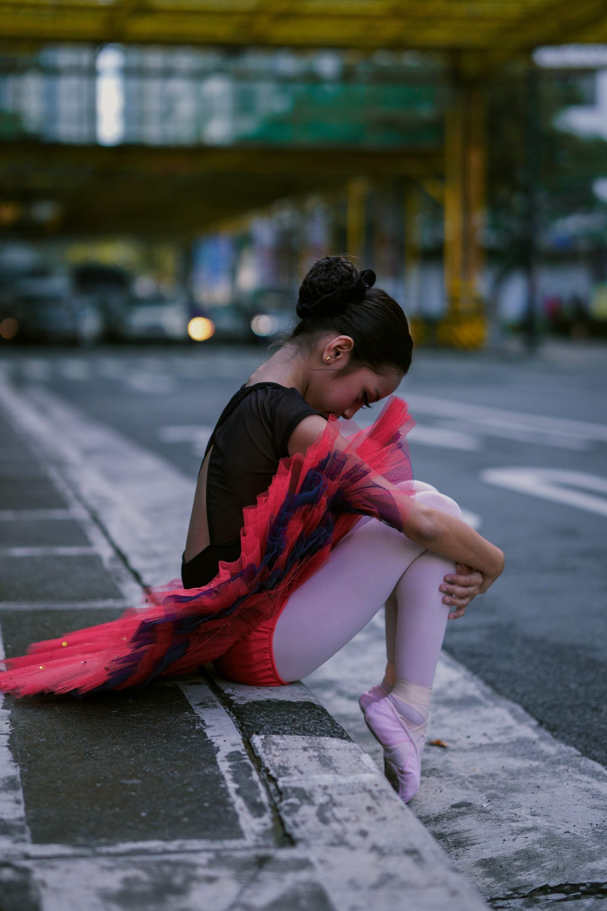 A young ballerina sad and sitting on the side of the street. | Source: Pexels. 