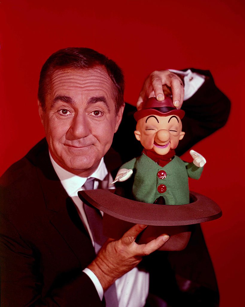 Jim Backus (1913-1989), US actor, holding a puppet of cartoon character 'Mr Magoo', in a studio portrait against a red background, circa 1965 | Photo: Getty Images