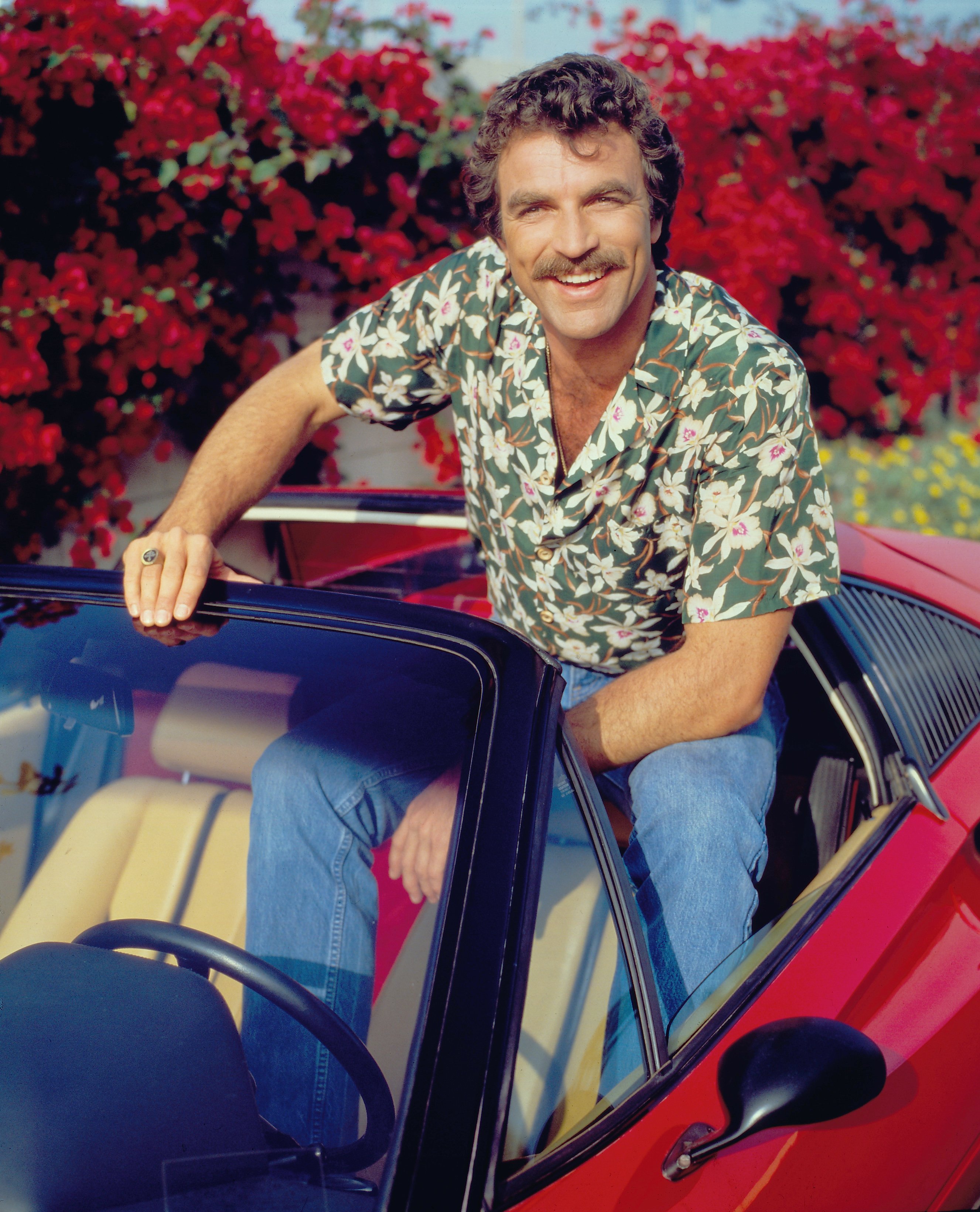 Tom Selleck pictured wearing a Hawaiian floral print shirt while sitting on a red Ferrari on January 1, 1984. | Photo: Getty Images