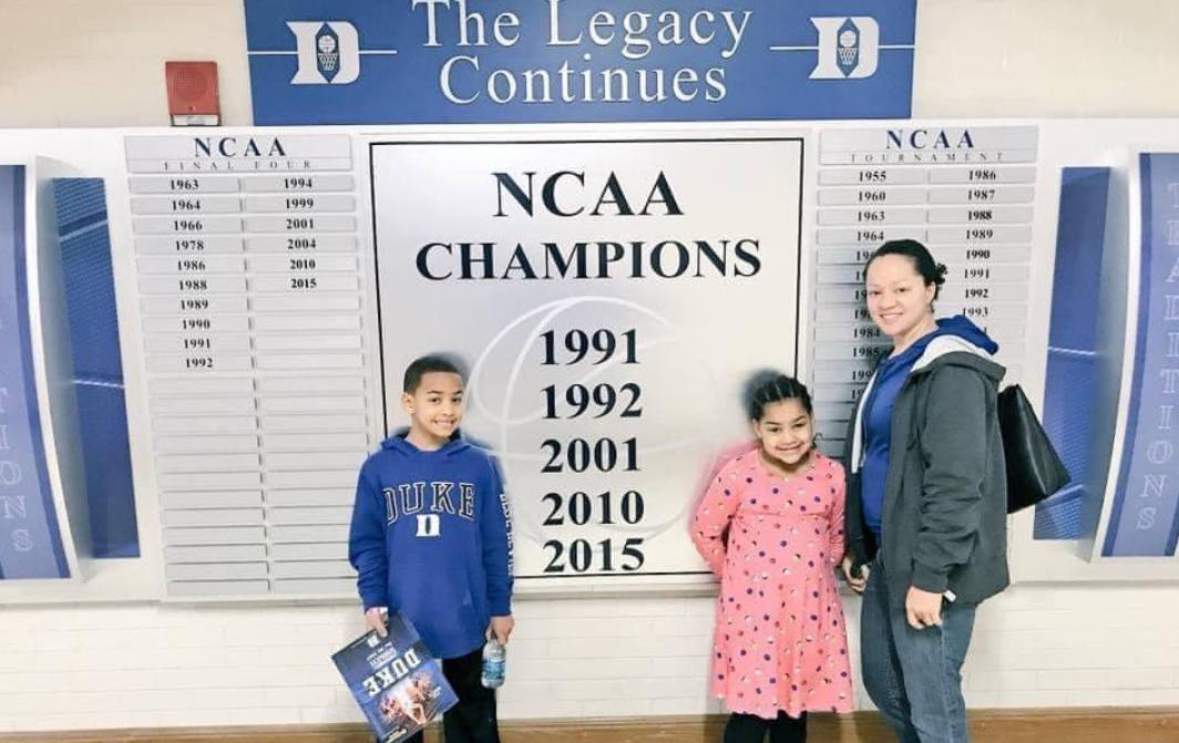 Cerina Fairfax stands with two children in front of a Duke University NCAA champions display during a campus visit | Source: Facebook/justin.fairfax.2025