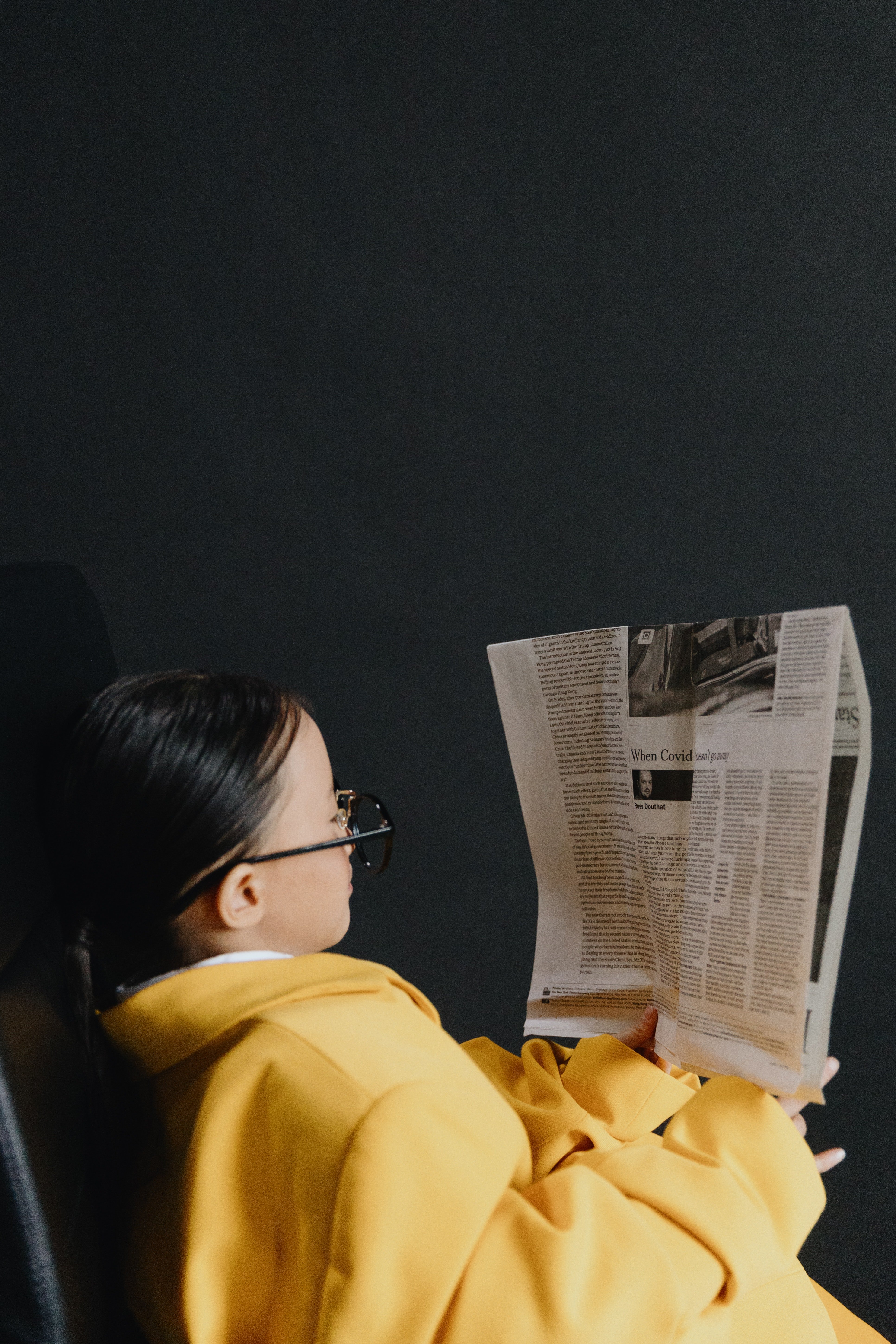 Una niña con lentes lee el periódico. | Foto: Pexels