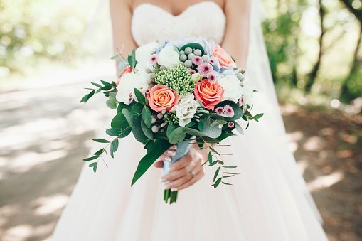 A bride holding bouquet of flowers outdoors.| Photo: Getty Images.