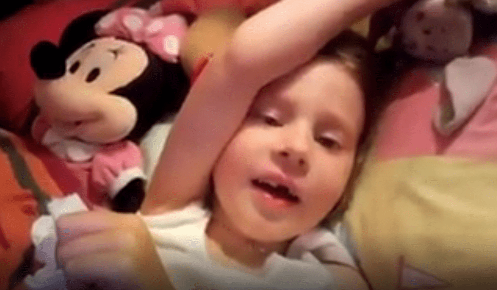 Zoé, sur un lit avec une poupée de Mini Mouse. | Capture d'écran de Facebook/Association Princesse Zoé atteinte de DIPG Zoé, sur un lit avec une poupée de Mini Mouse. | Capture d'écran de Facebook/Association Princesse Zoé atteinte de DIPG