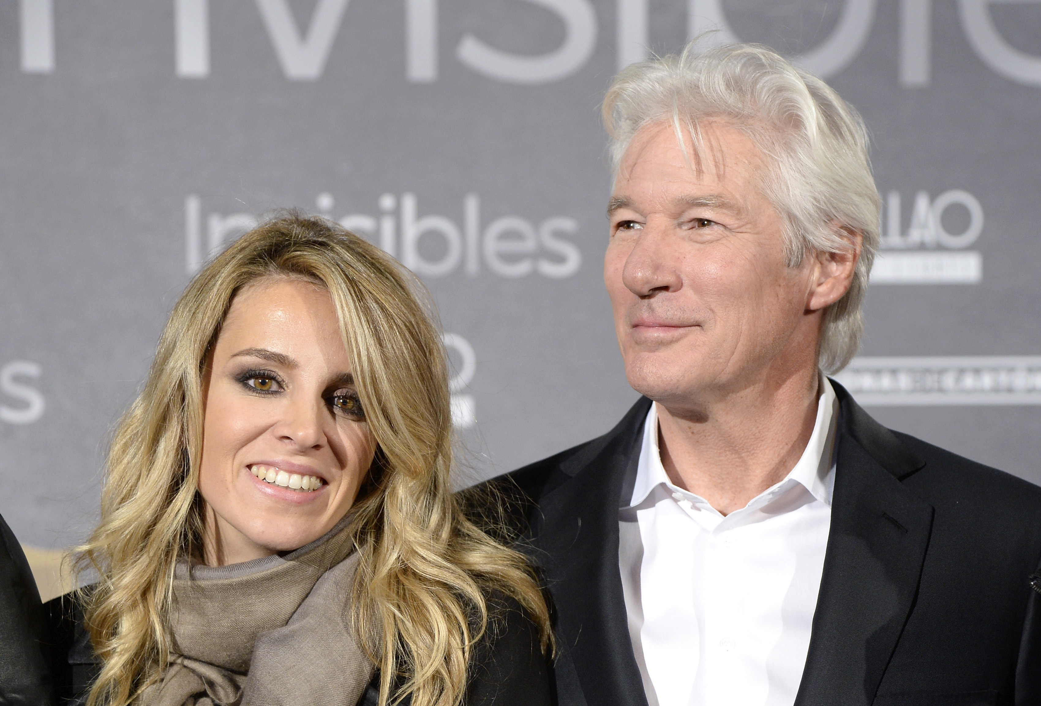 Richard Gere and Alejandra Silva appeared at the Madrid premiere of Invisibles on March 2, 2020. She wore a taupe scarf and gray coat over soft waves, while Gere opted for a crisp white shirt and black blazer, both smiling against the press wall.