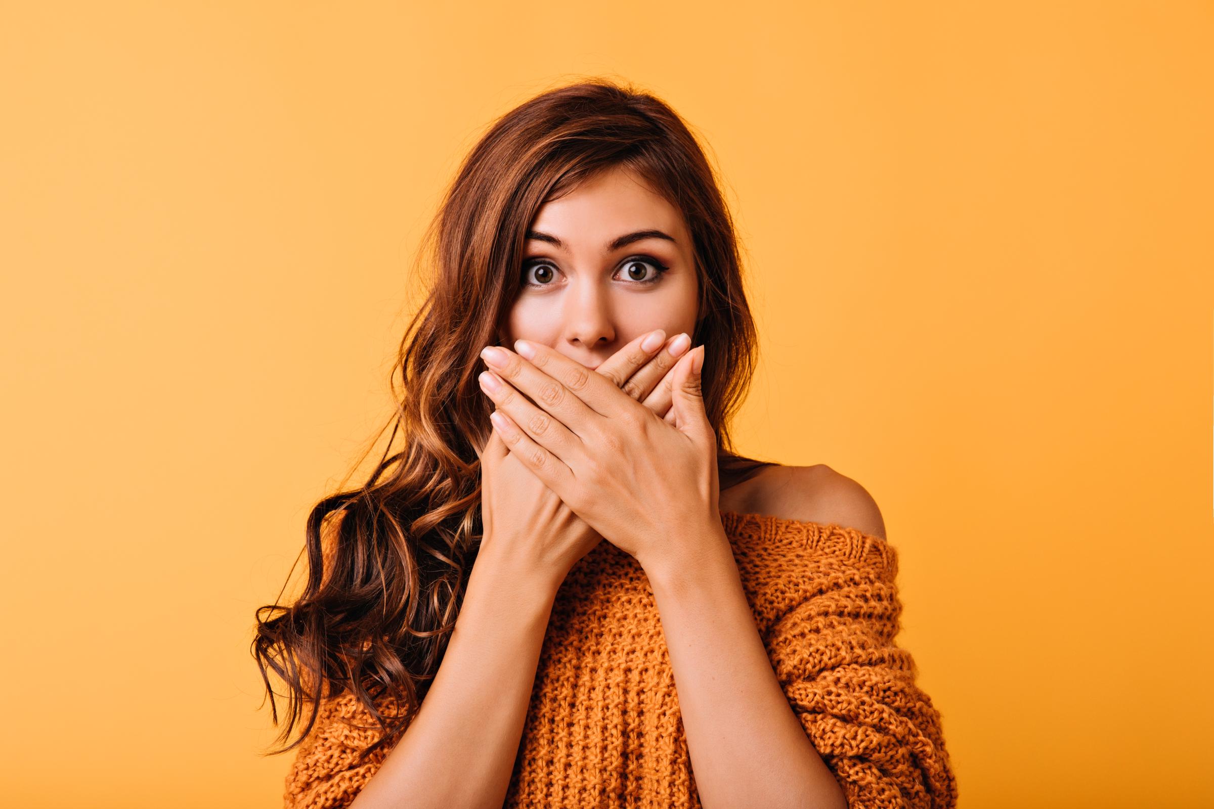 A surprised young woman covering her mouth | Source: Freepik