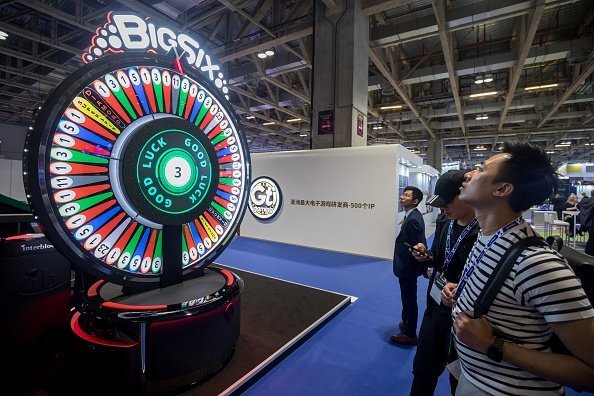 Attendees stand in front of a Big Six wheel of fortune at the Global Gaming Expo Asia (G2E Asia) in Macau, China, on Tuesday, May 21, 2019 | Photo: Getty Images