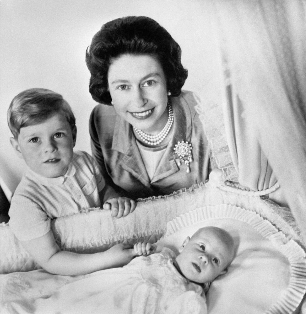 El Príncipe Edward junto a la Reina de Inglaterra agarrando el dedo de su hermano, el Príncipe Andrew. | Foto: Getty Images.